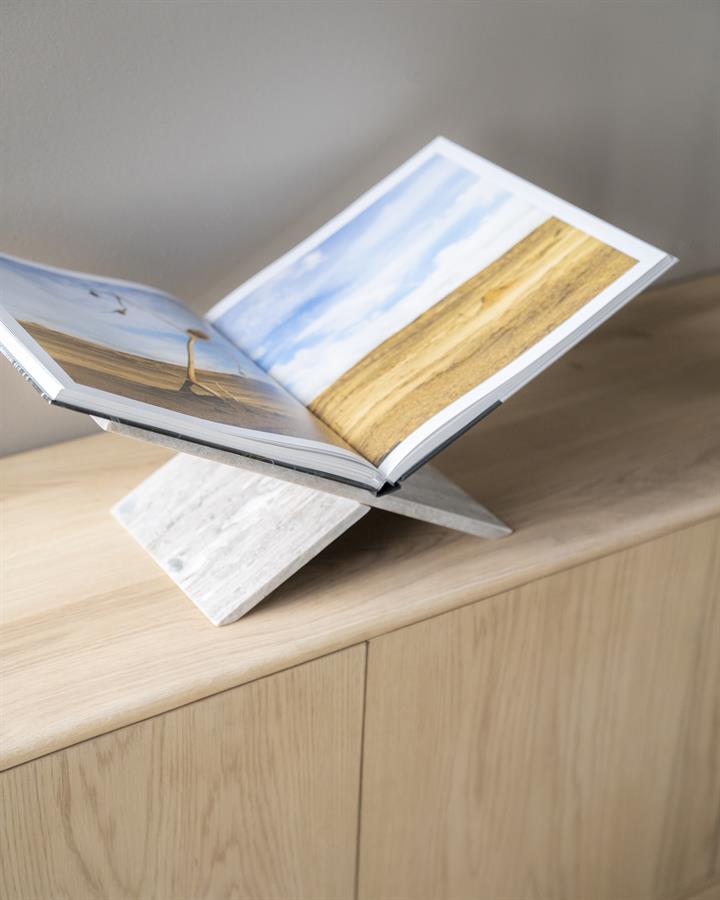Der Tsun Buchständer aus weißem Marmor zeigt ein offenes Buch auf einem hellen Holzschrank - By-Boo