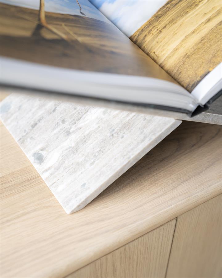 Detailaufnahme des Tsun, eines Marmoruntersetzers unter einem offenen Buch auf einem Holztisch - By-Boo