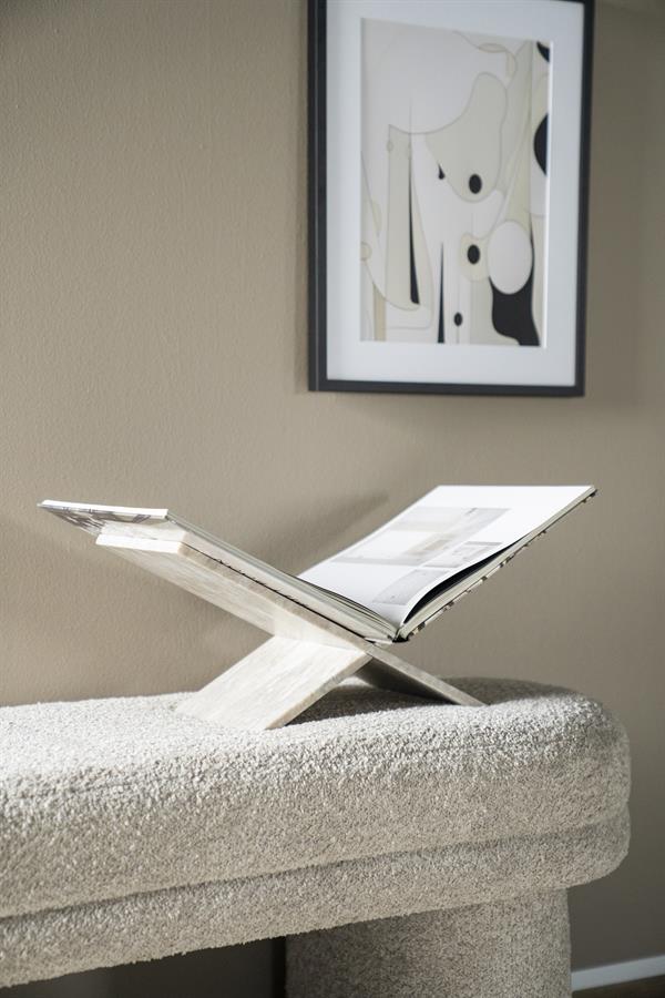 Der Tsun Buchständer mit einem offenen Buch darauf, auf einem hellgrauen Pouf in einem Interieur stehend - By-Boo