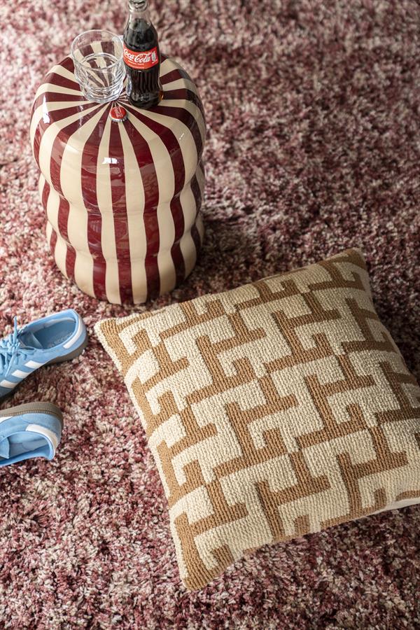 Das Kissen Ziggy mit beigem und braunem geometrischem Muster liegt auf einem lila Shaggy-Teppich - By-Boo