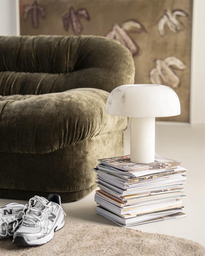 Die Leuchte GlowStone steht auf einem Zeitschriftenstapel neben einem grünen Sofa, mit Turnschuhen davor - By-Boo