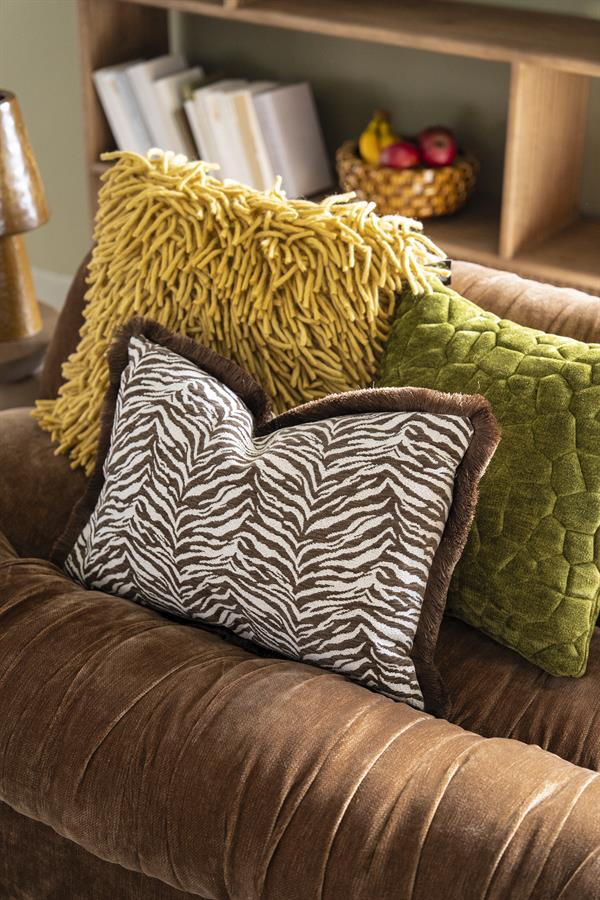 Drei Kissen auf einem braunen Sofa, darunter das Kissen Stitch Grün, in einem stimmungsvollen Wohnzimmer - By-Boo