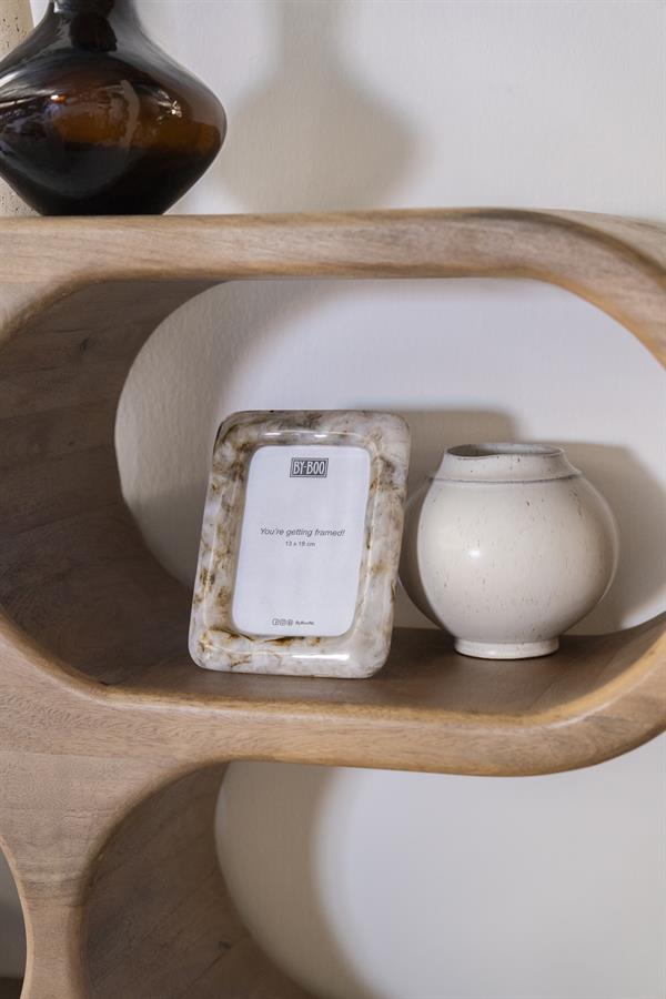 Ein By-Boo Bilderrahmen Framea 1 und eine cremefarbene Vase auf einem Holzregal