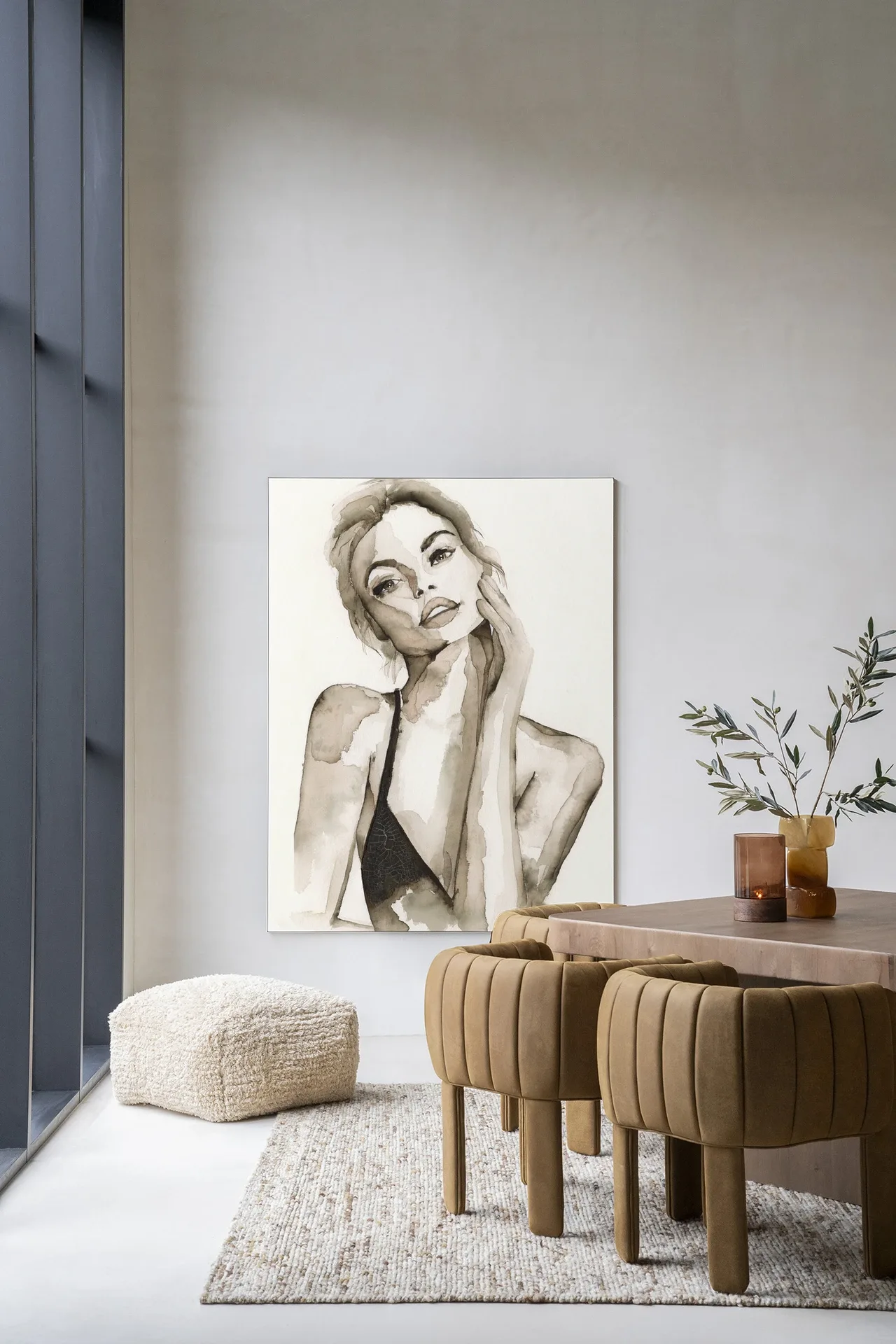Wandteppich A Woman's Face von Urban Cotton hängt an einer hellen Wand über einem Pouf