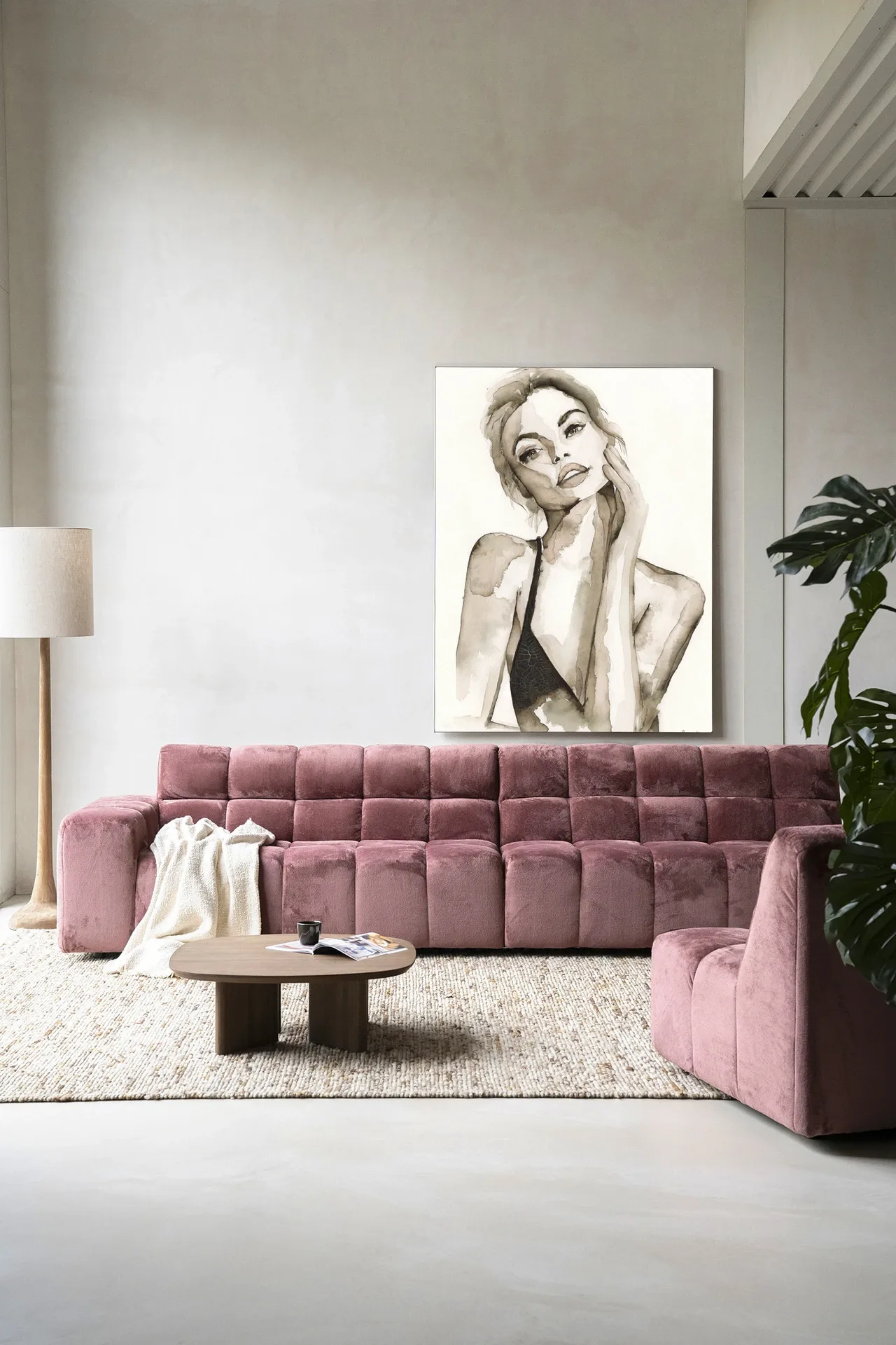 Wandteppich A Woman's Face von Urban Cotton hängt über einem rosa Sofa in einem modernen Wohnzimmer
