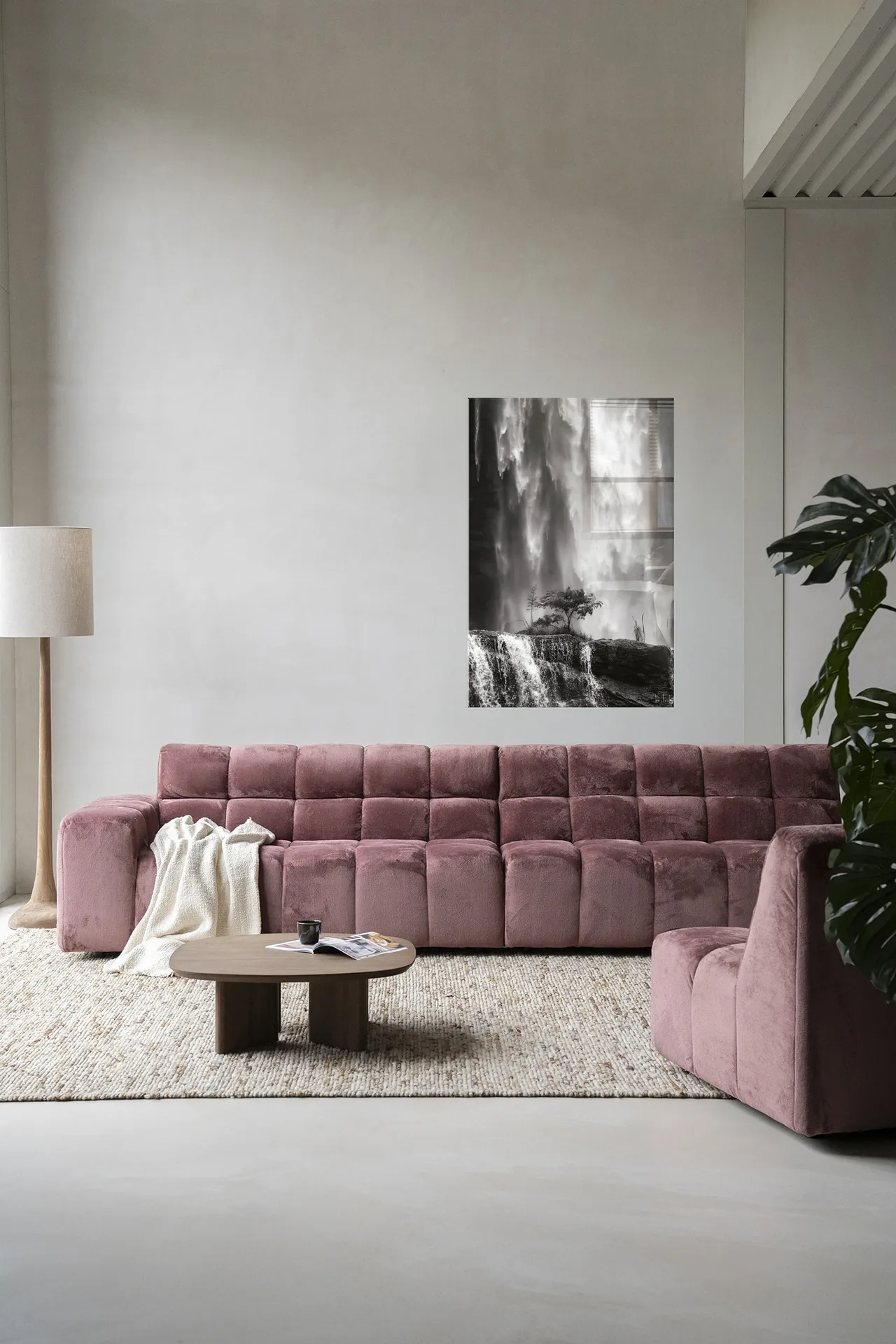Wandkleed Germinate - Urban Cotton hangt aan een lichte muur boven een roze bank in een woonkamer
