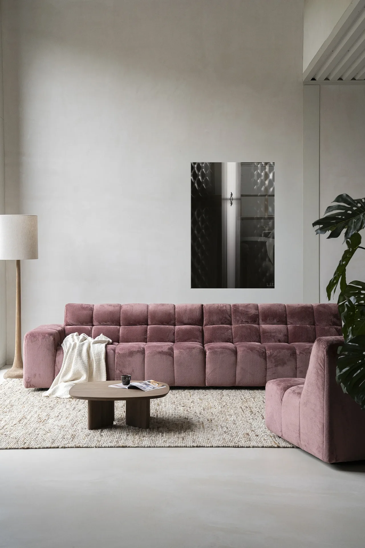 Wandkleed Passing - Urban Cotton hangt aan een lichte muur boven een roze bank in een woonkamer