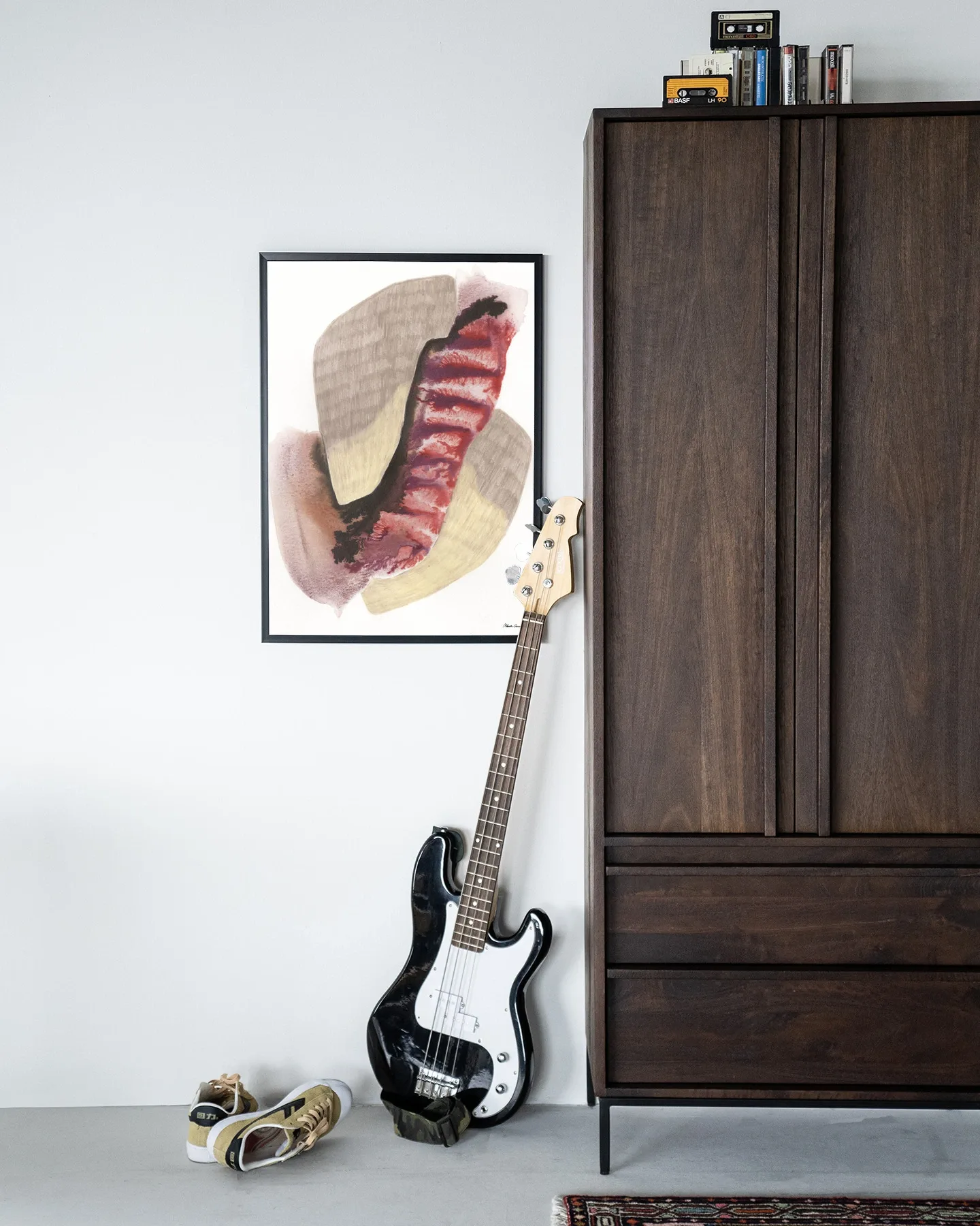 Wandkleed Embrace - Urban Cotton hangt aan een witte muur naast een donkerbruine kast