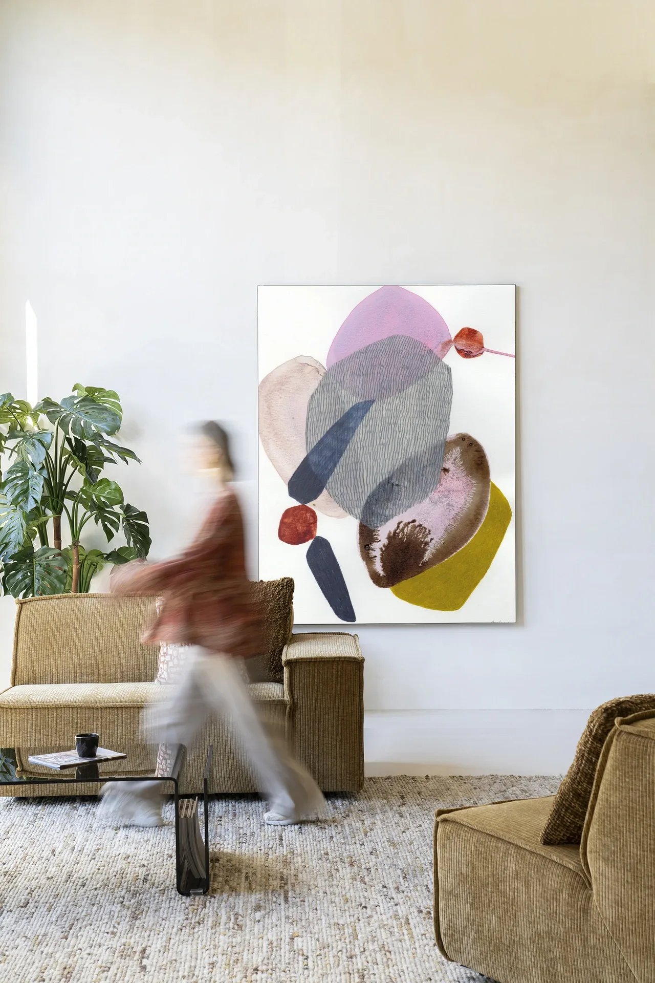 Ein lebhaftes Wohnzimmer mit dem Wandteppich Wings - Urban Cotton an einer weißen Wand, einem Sofa und einem Couchtisch