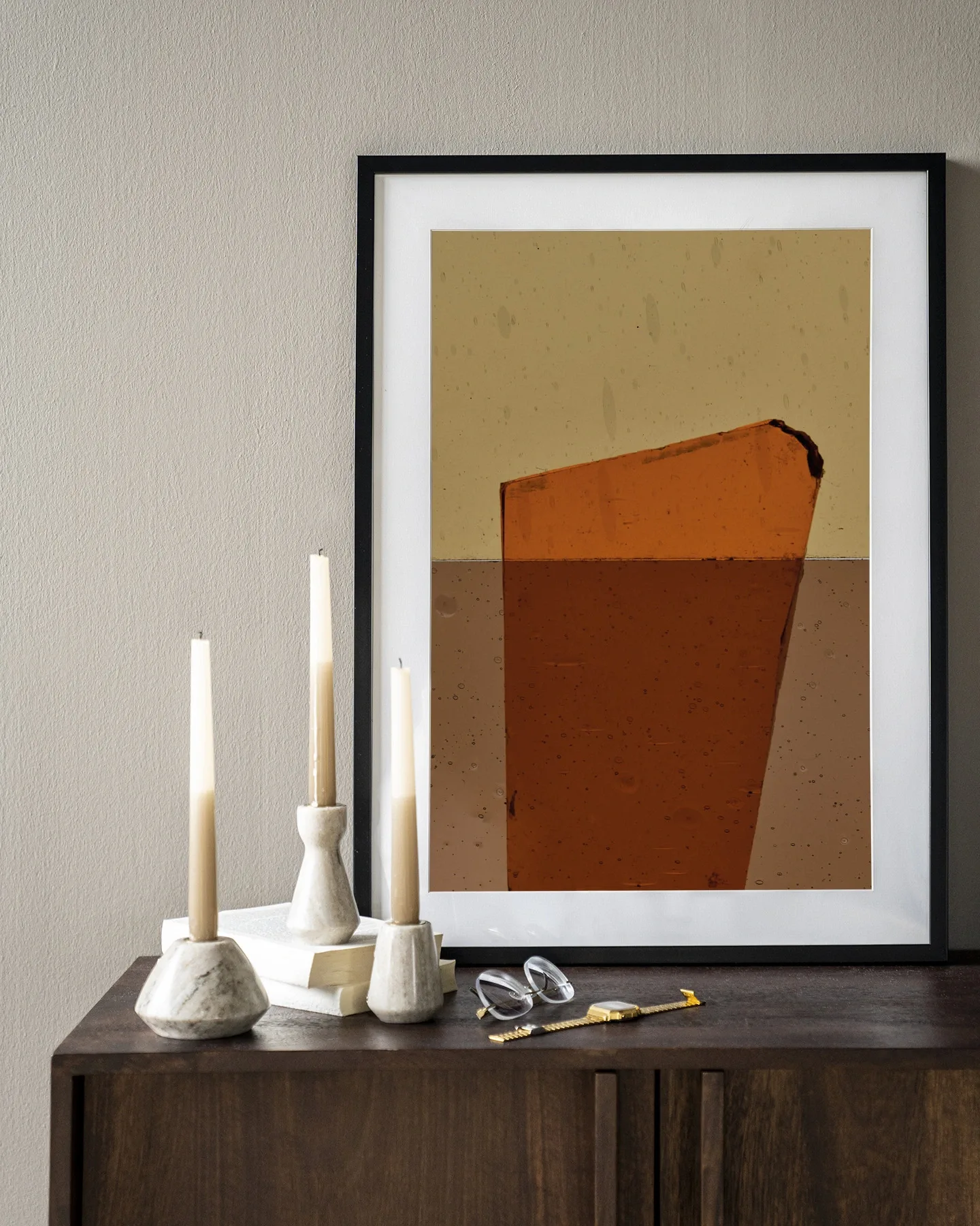 Wandkleed Oranje - Urban Cotton hangend boven een houten dressoir met kaarsen en bril