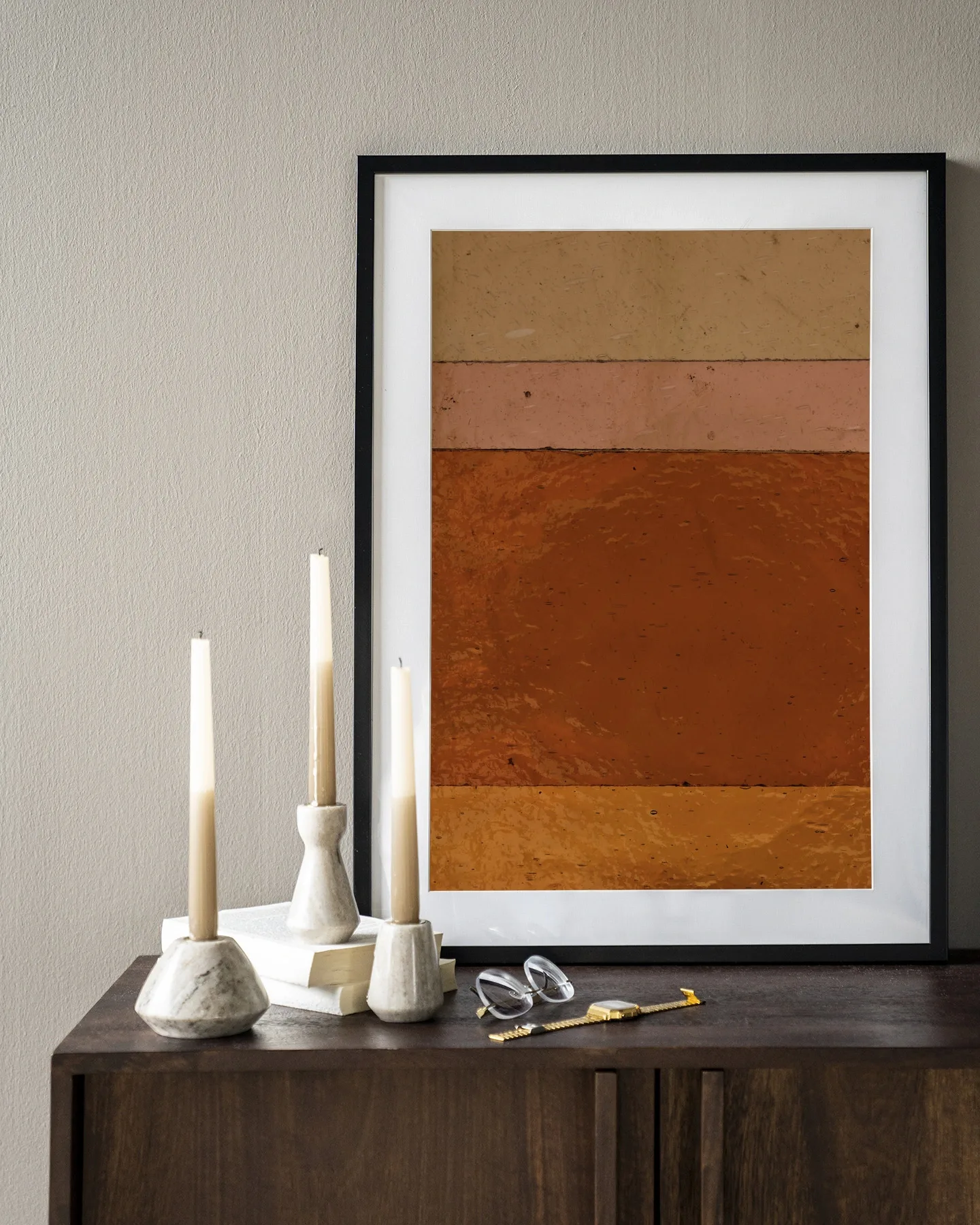 Wandteppich Braunrosa - Urban Cotton im Rahmen, stehend auf einem dunkelbraunen Sideboard mit Kerzen und einer Brille
