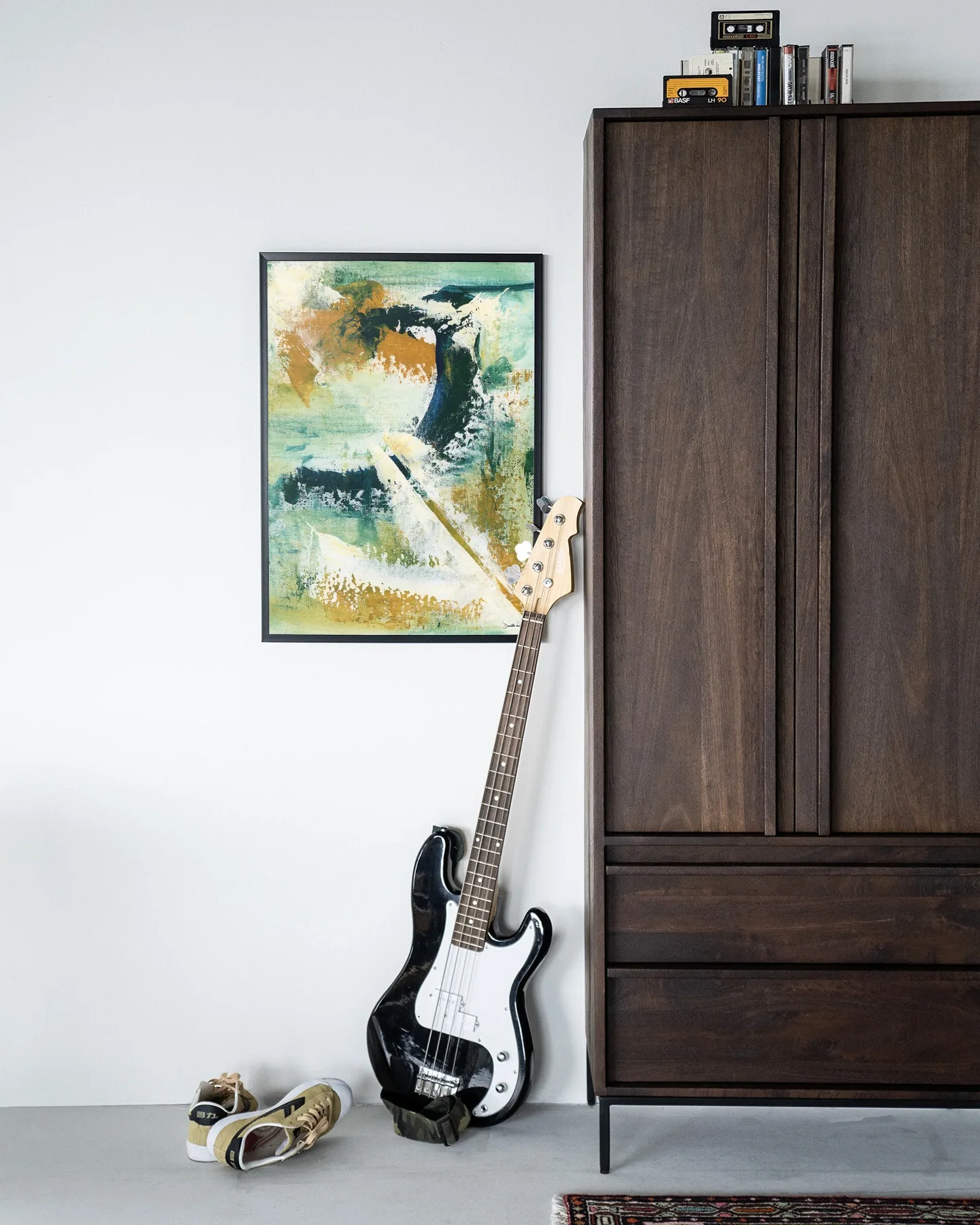 Der Art Print Mood - Urban Cotton hängt an einer weißen Wand neben einem dunkelbraunen Schrank mit einer Bassgitarre davor