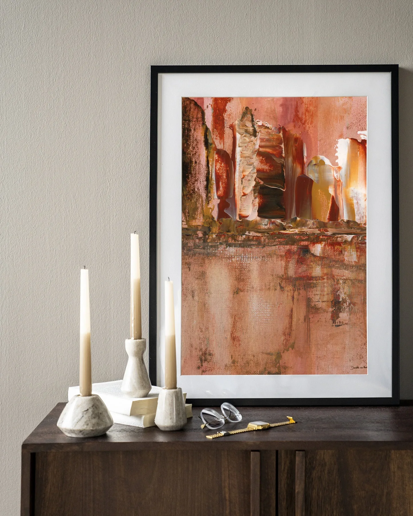 Art Print Skyline - Urban Cotton in einem schwarzen Rahmen, stehend auf einem dunkelbraunen Schrank mit Kerzen und einer Brille