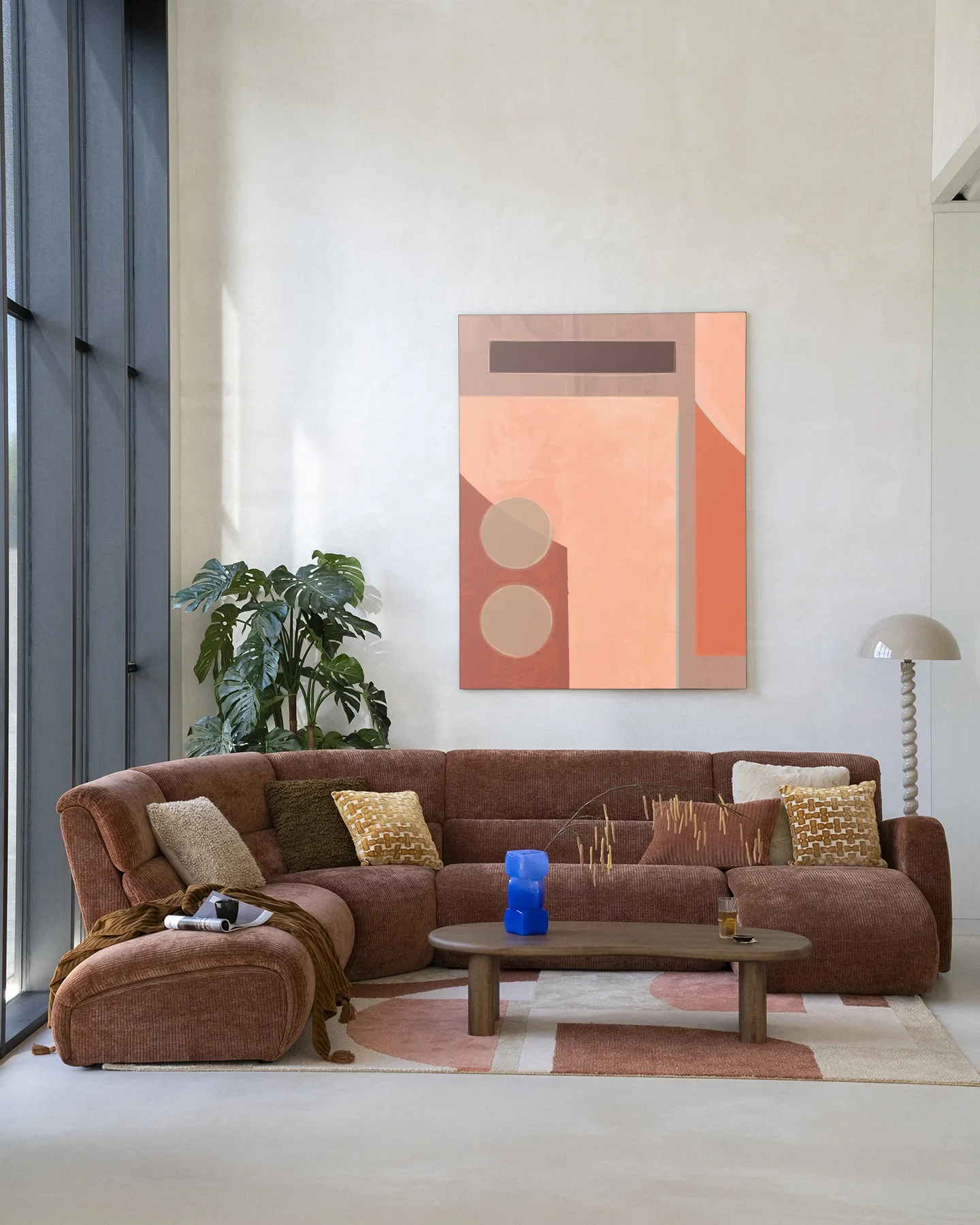 Ein braunes Modulsofa mit Kissen steht vor dem Wandteppich Monolithic - Urban Cotton in einem modernen Wohnzimmer