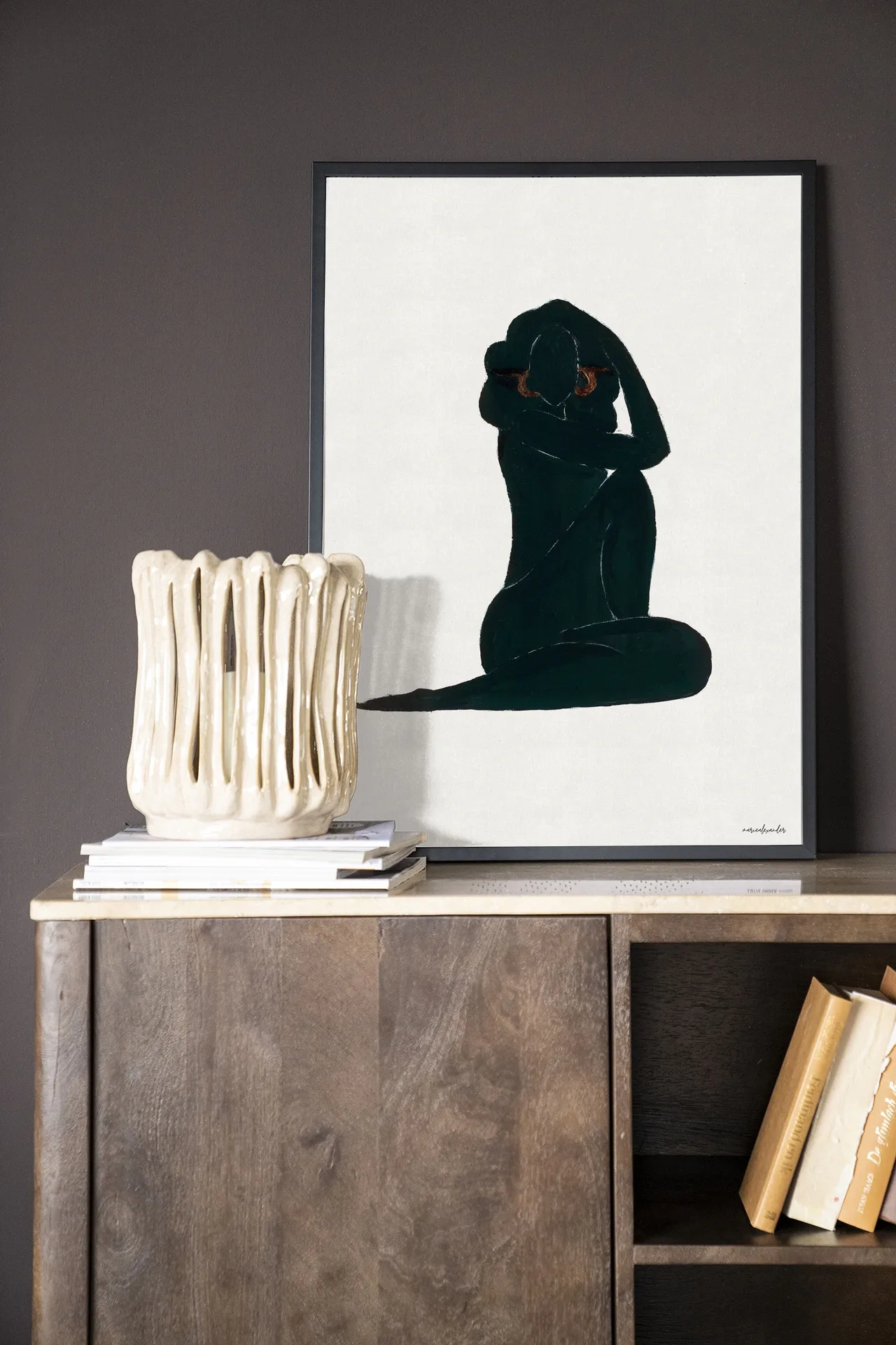 Wandteppich Stillness - Urban Cotton hängt über einer Holzkommode mit Büchern und einer Vase