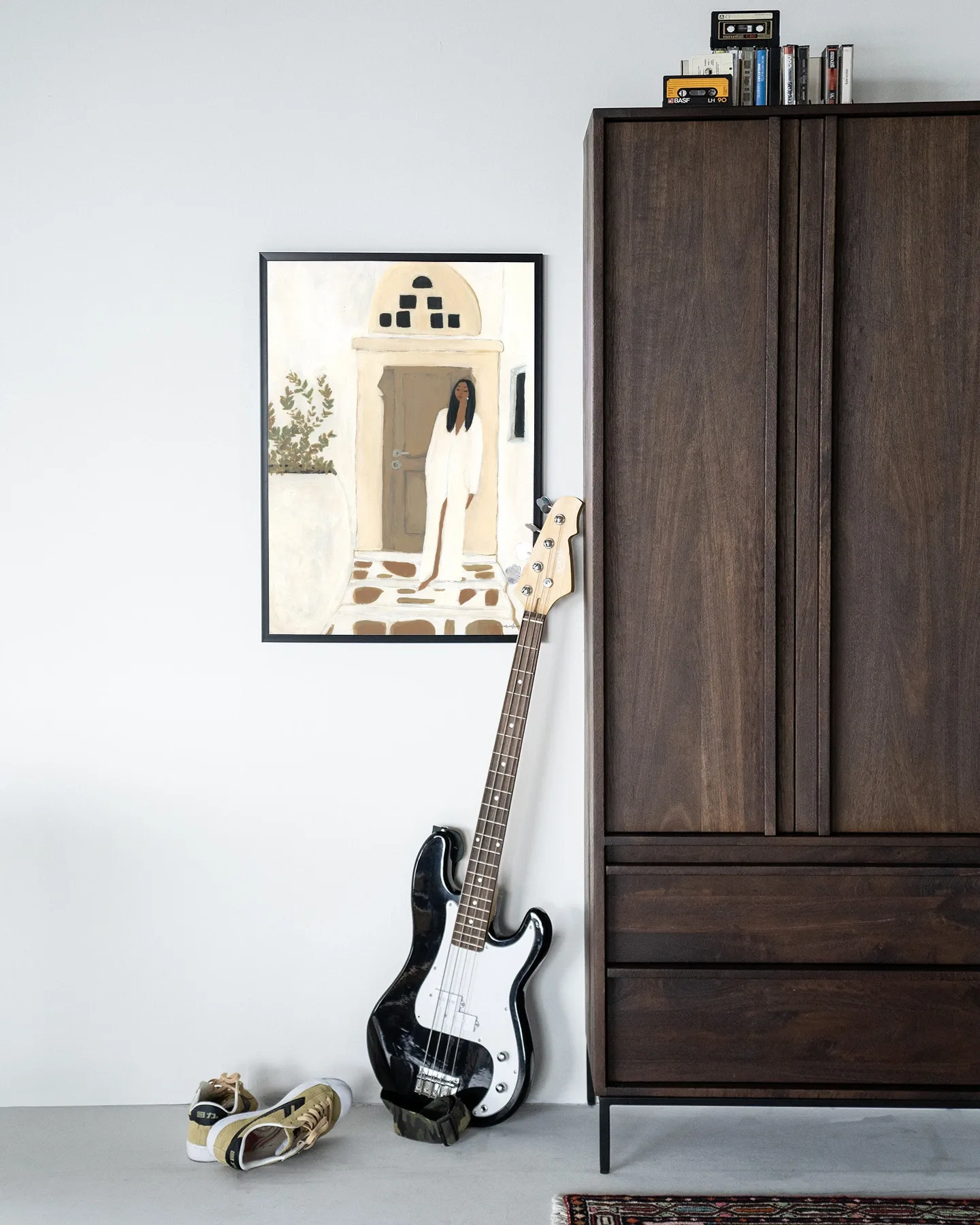 Wandkleed Mediterranean Dream - Urban Cotton hangend aan een witte muur, met een basgitaar en schoenen eronder