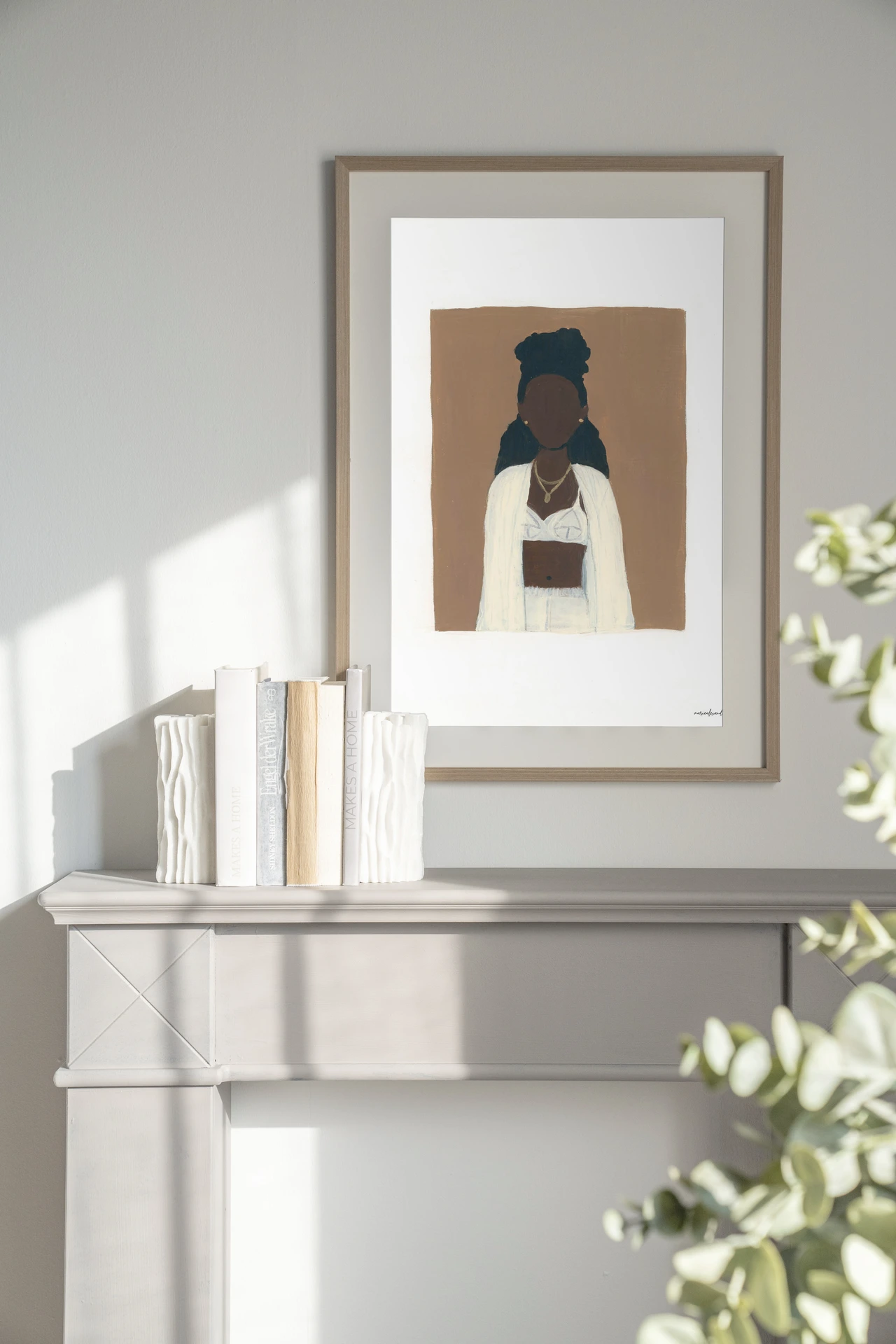 Kunstdruck Slow Living - Urban Cotton hängt über einem hellen Kaminsims mit Büchern und Vasen