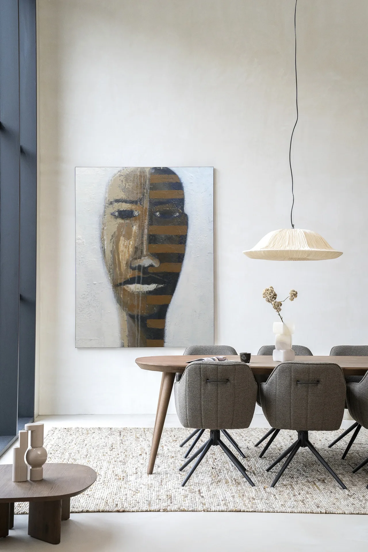 Wandteppich Head 1 - Urban Cotton hängt an einer hellen Wand über einem Esstisch aus Holz