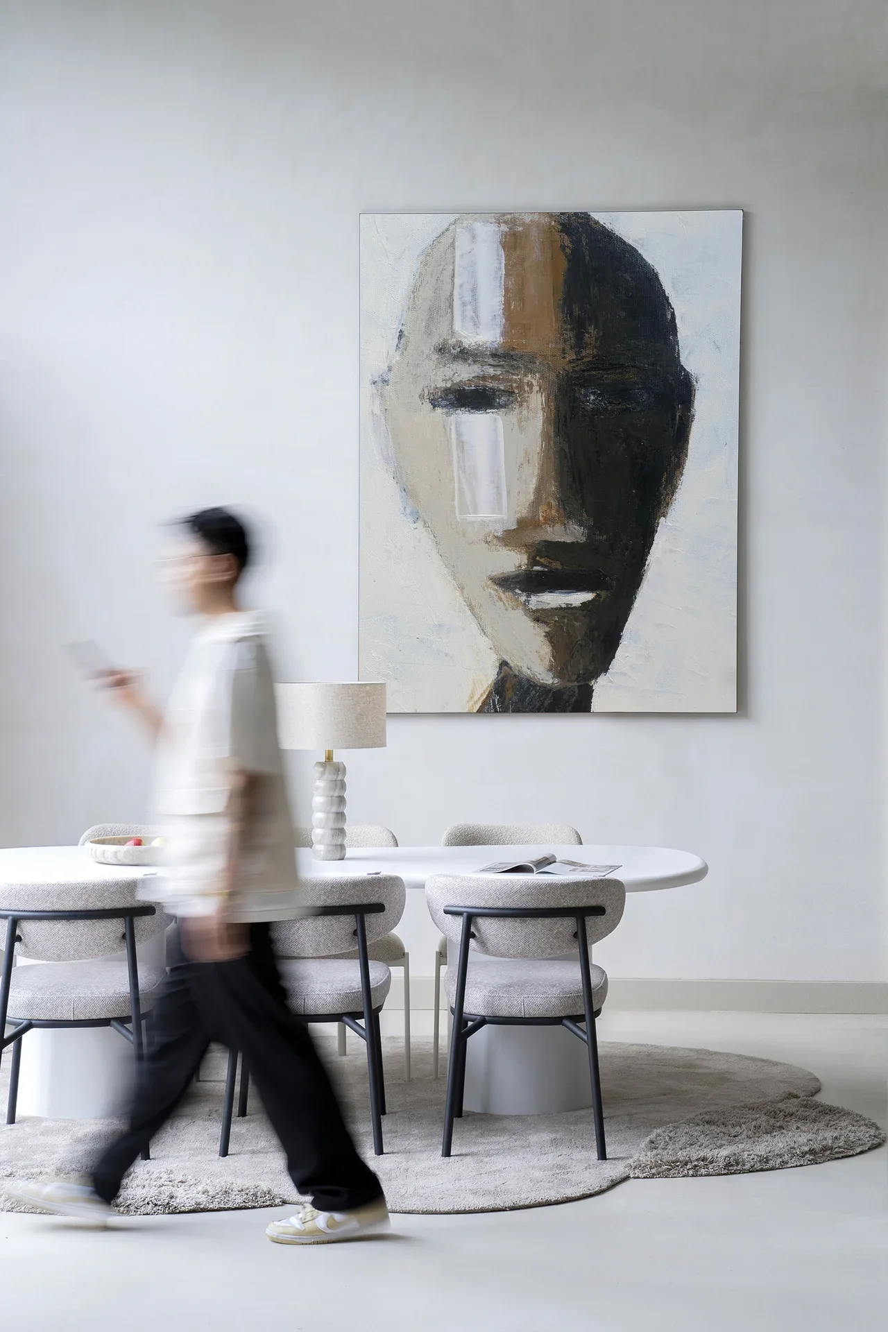 Wandteppich Head 2 - Urban Cotton hängt an einer weißen Wand über einem Esstisch mit Stühlen