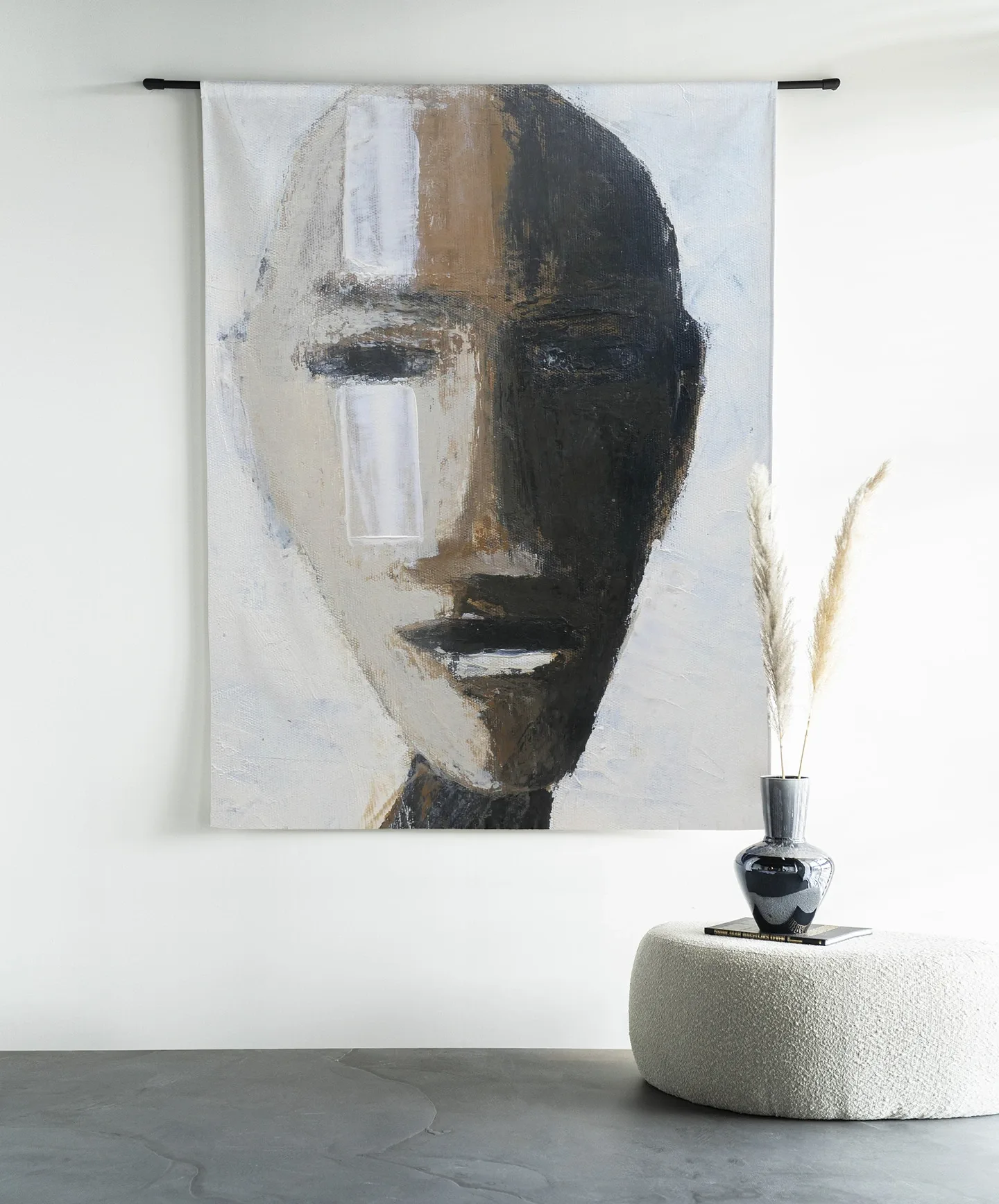 Wandteppich Head 2 an einer schwarzen Stange, mit einer Vase und Pampasgras auf einem Hocker daneben - Urban Cotton
