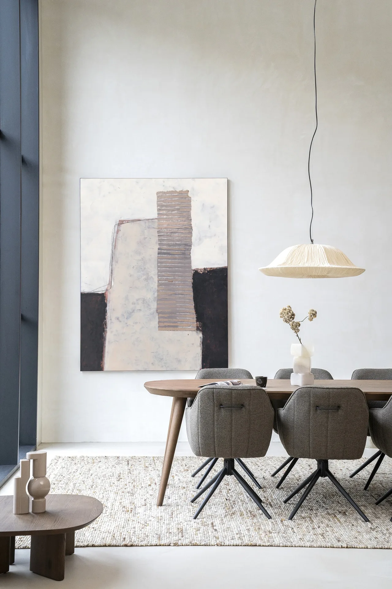 Wandteppich Abstract 1 - Urban Cotton hängt an einer weißen Wand über einem Holzesstisch