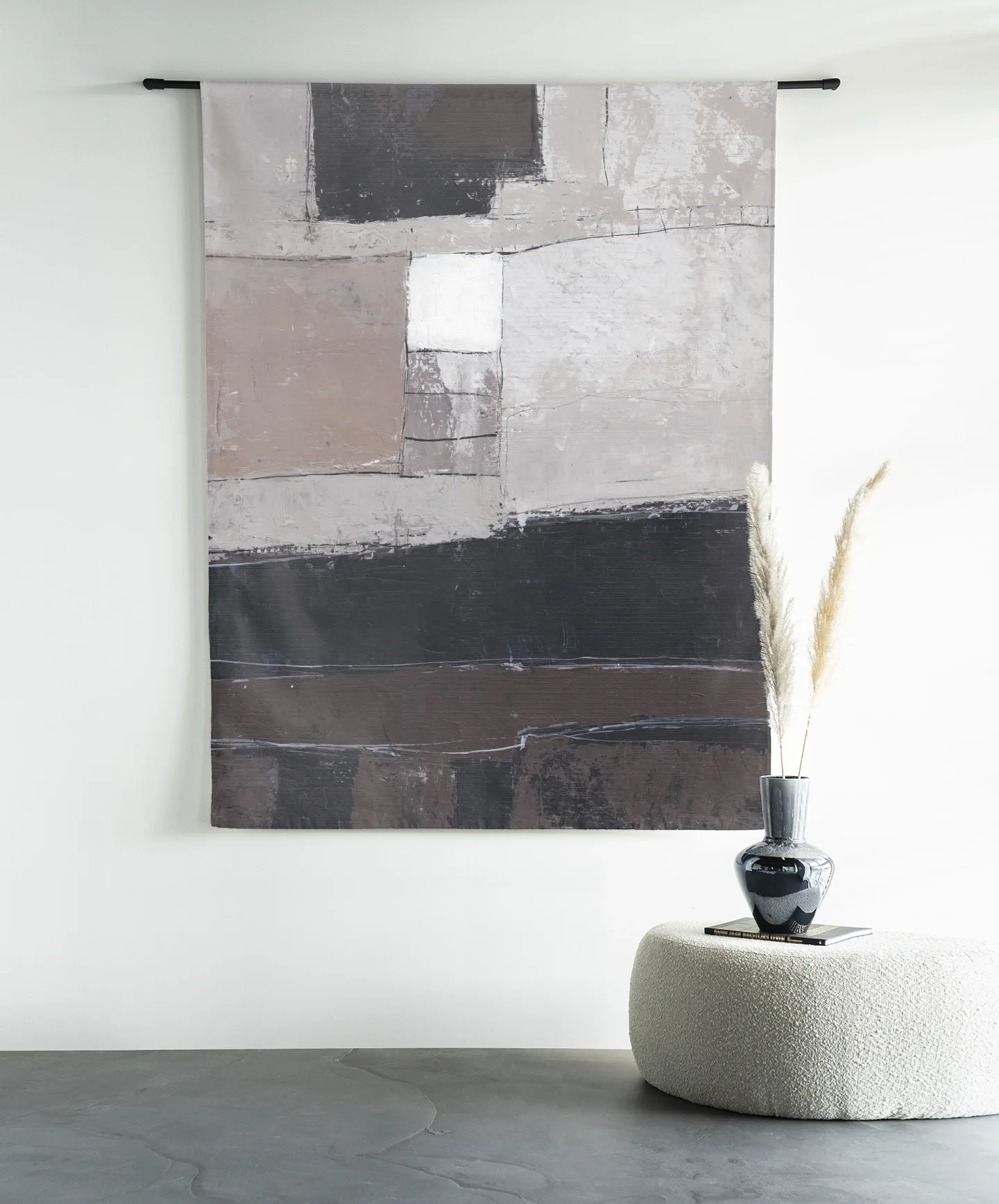 Wandteppich Abstract 4 - Urban Cotton hängt an einer schwarzen Stange über einem Pouf mit Dekoration