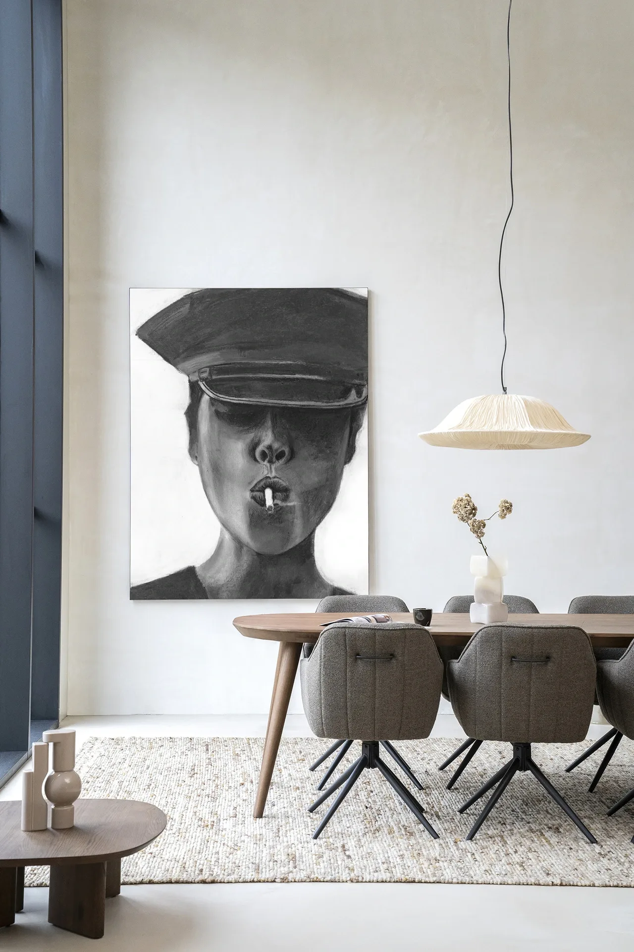 Wandteppich Smokes - Urban Cotton hängt an einer weißen Wand in einem modernen Interieur mit Esstisch