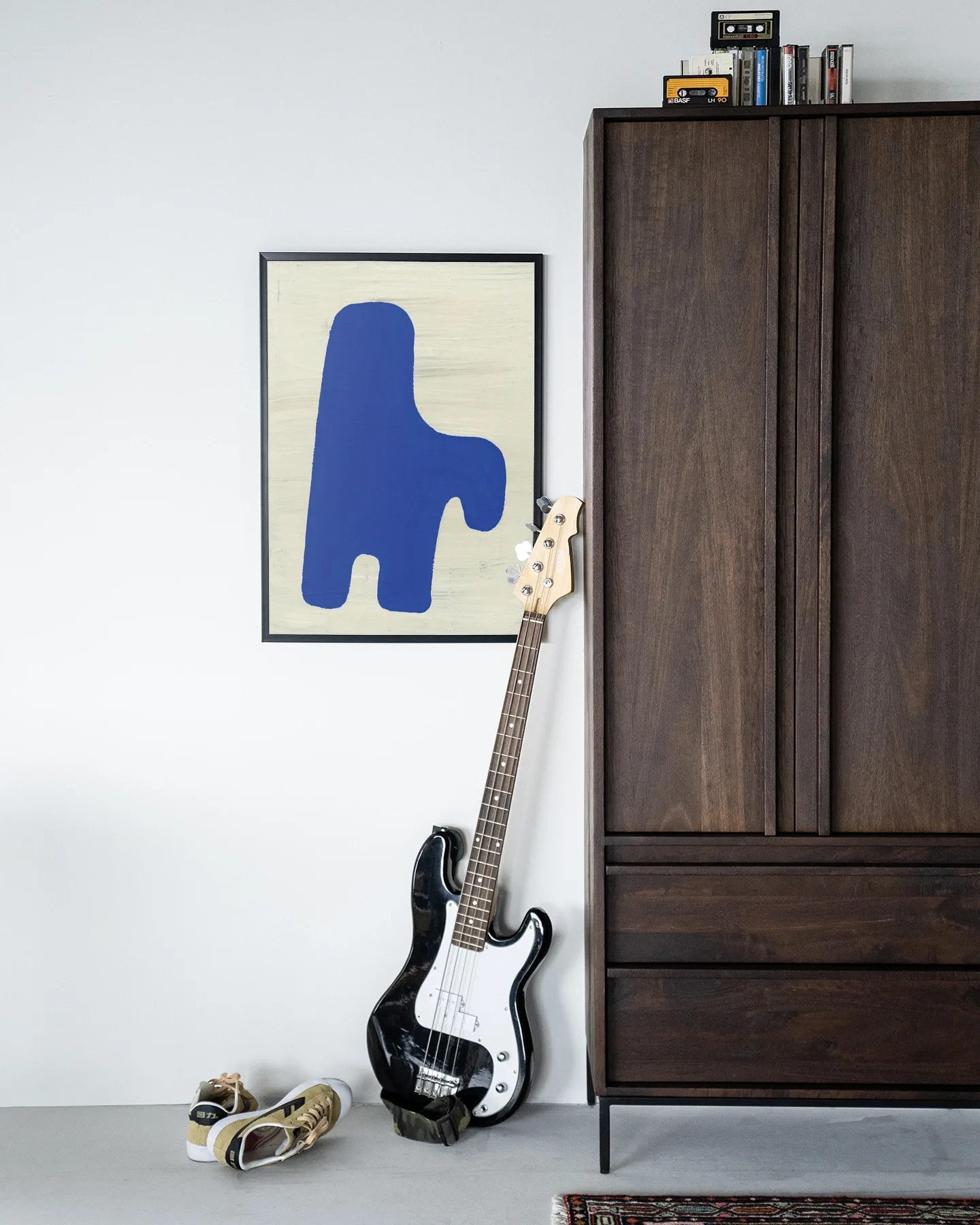Wandteppich Cobby - Urban Cotton an einer weißen Wand in einem modernen Interieur mit Bassgitarre und Schrank
