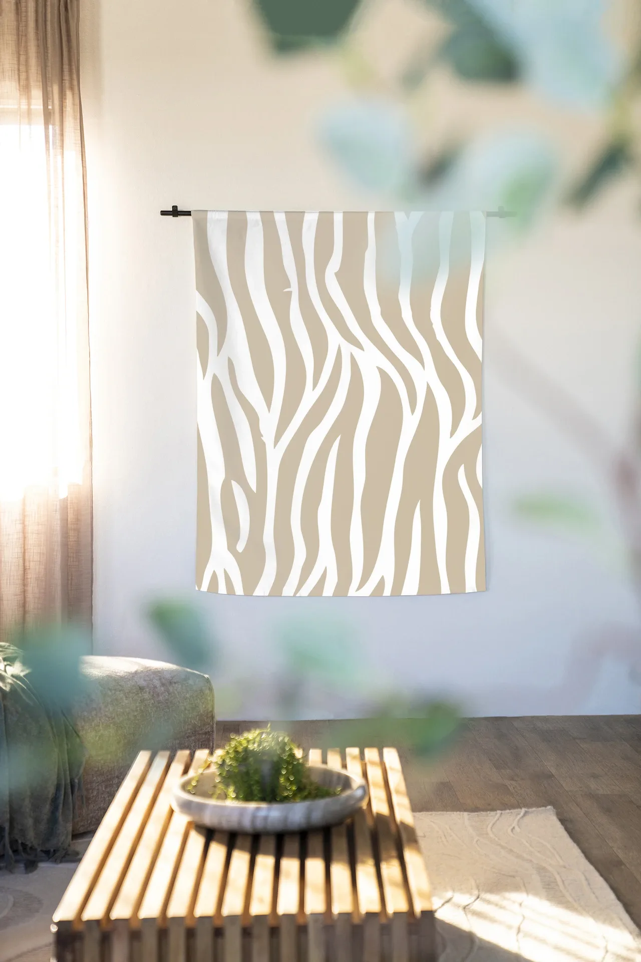 Wandteppich Savanna Beige - Urban Cotton hängt an einer schwarzen Stange in einem hellen Wohnzimmer mit Pflanzen und einem Couchtisch