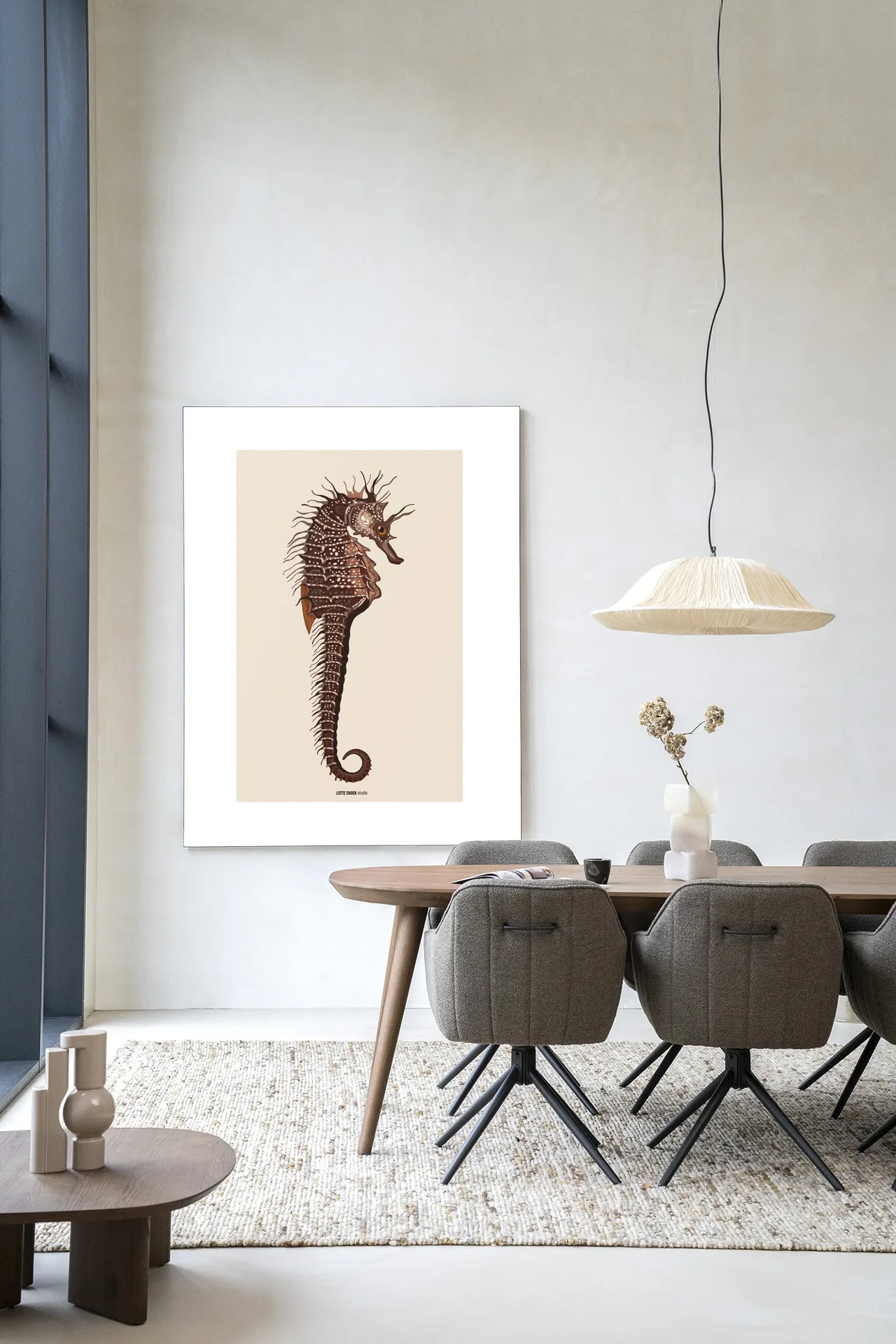 Art print Maona - Urban Cotton hangt aan een witte muur boven een houten eettafel met grijze stoelen