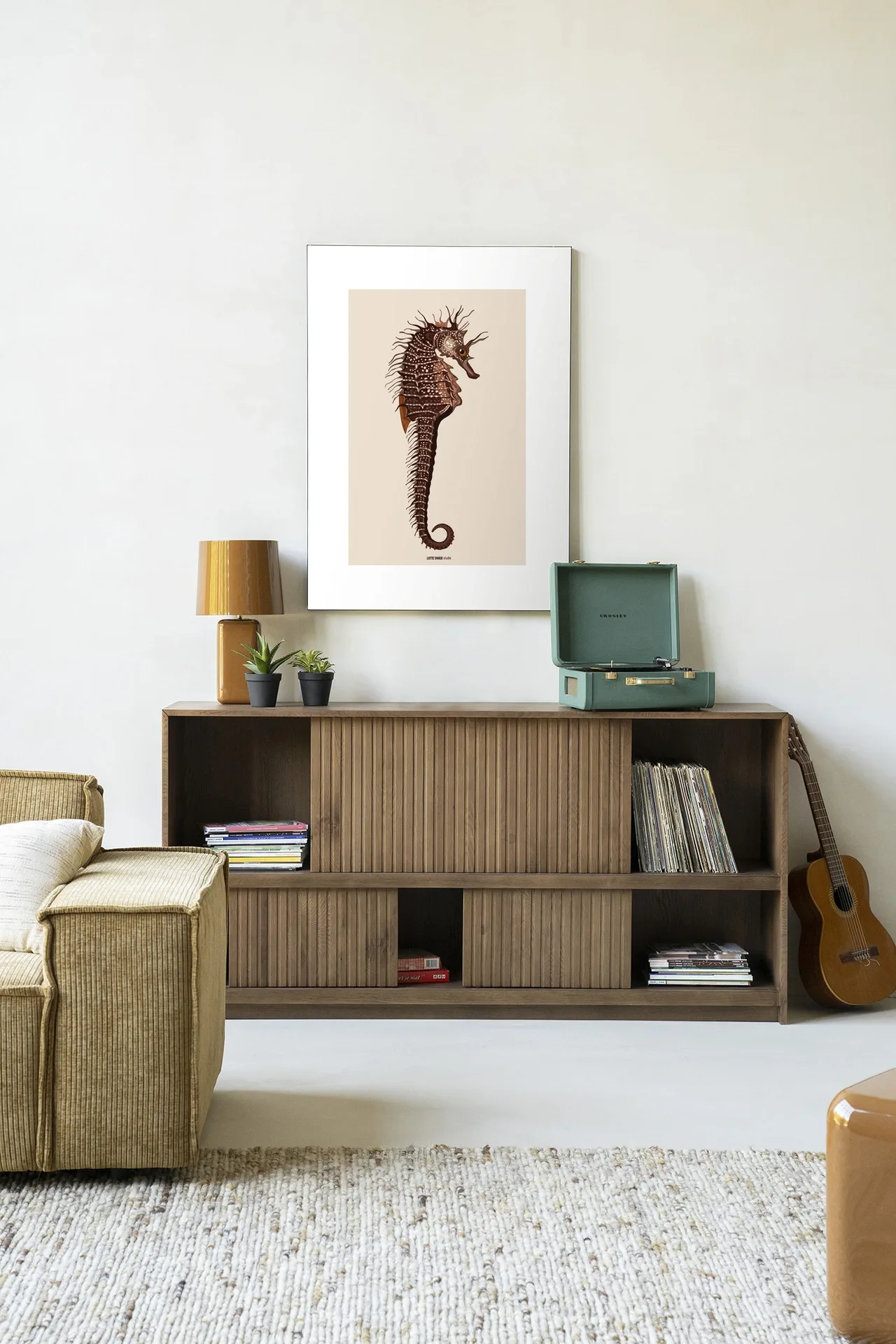 De Art print Maona - Urban Cotton hangt boven een houten dressoir in een lichte woonkamer