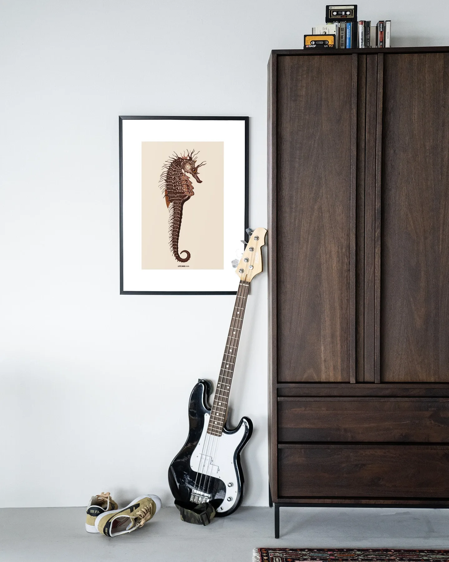 Art print Maona - Urban Cotton hangend aan een witte muur met een basgitaar en schoenen ervoor
