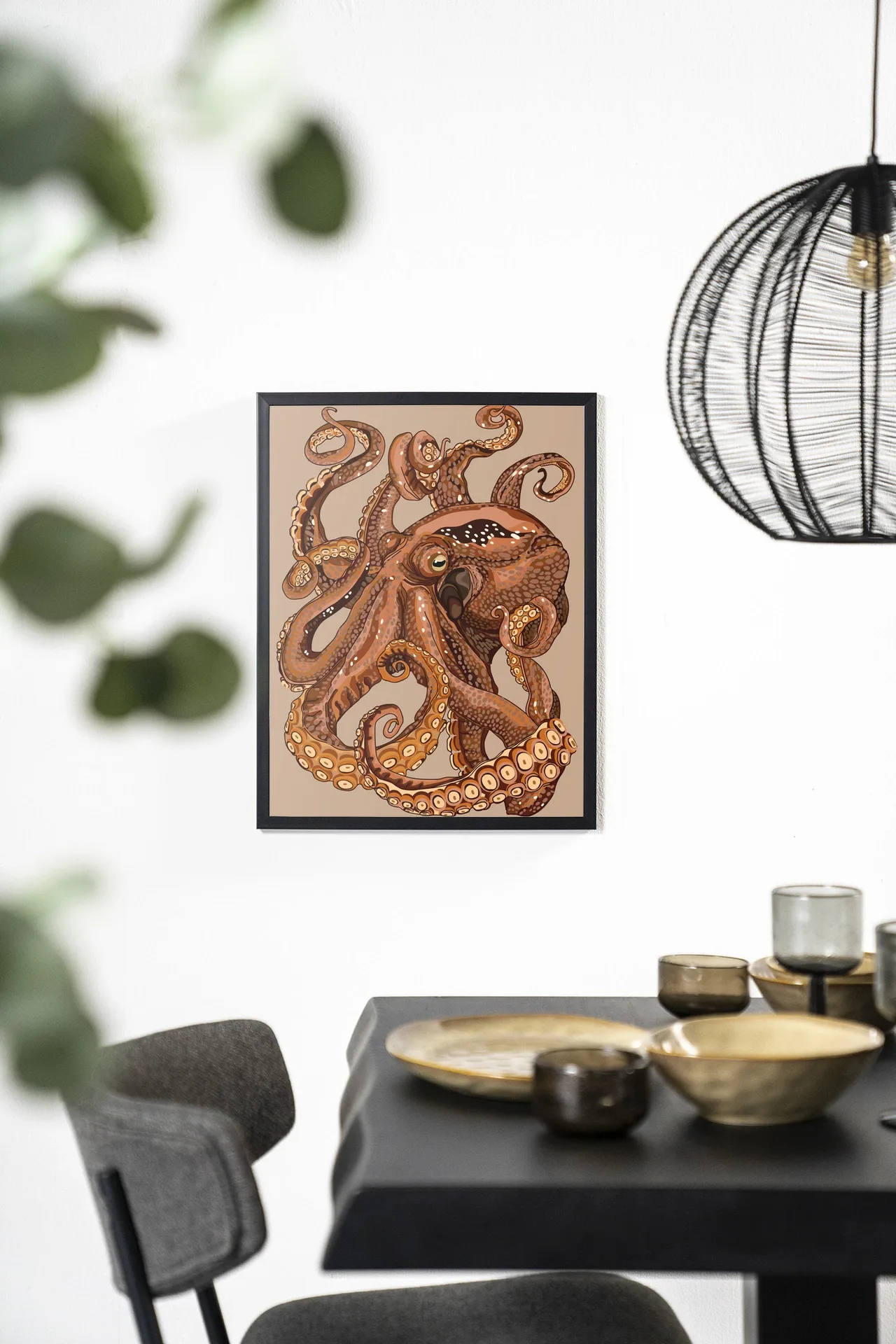 Wandteppich Pulpo - Urban Cotton hängt an einer weißen Wand über einem schwarzen Esstisch mit goldenen Schalen