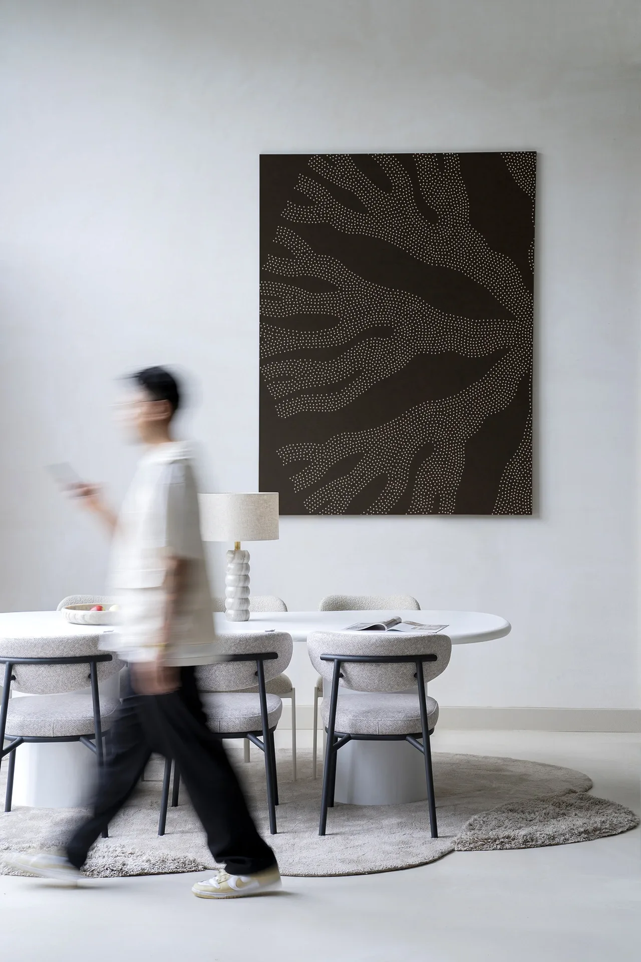 Wandteppich Circle Dark von Urban Cotton hängt in einem modernen Esszimmer, eine Person läuft vorbei