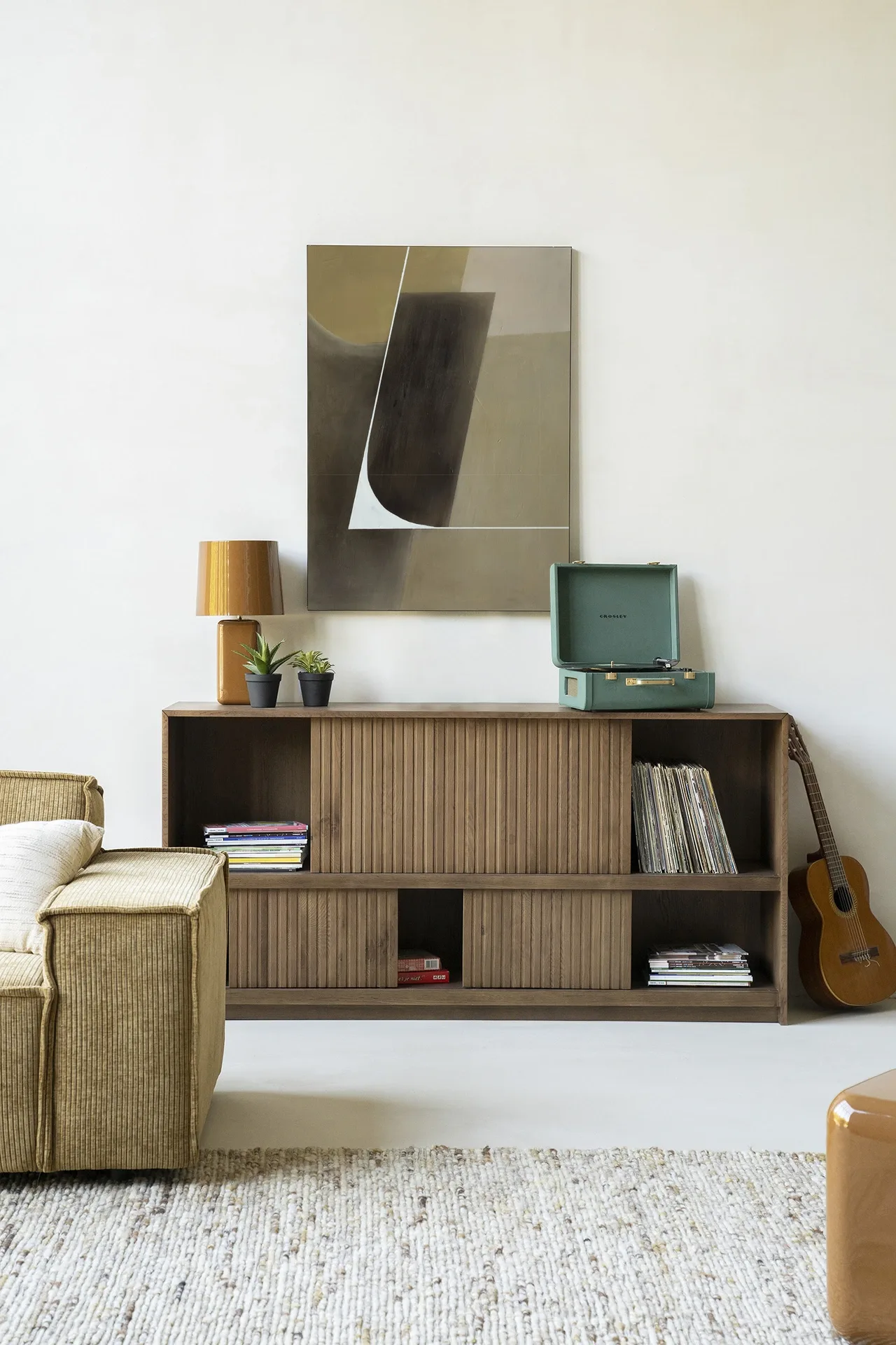 Wandkleed Gentleness - Urban Cotton hangt boven een houten dressoir met planten en een platenspeler