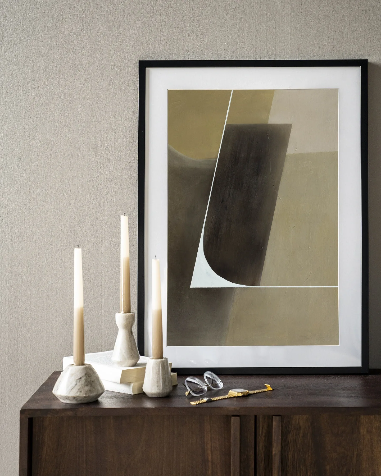 Wandkleed Gentleness - Urban Cotton, ingelijst boven een houten dressoir met kaarsen en boeken