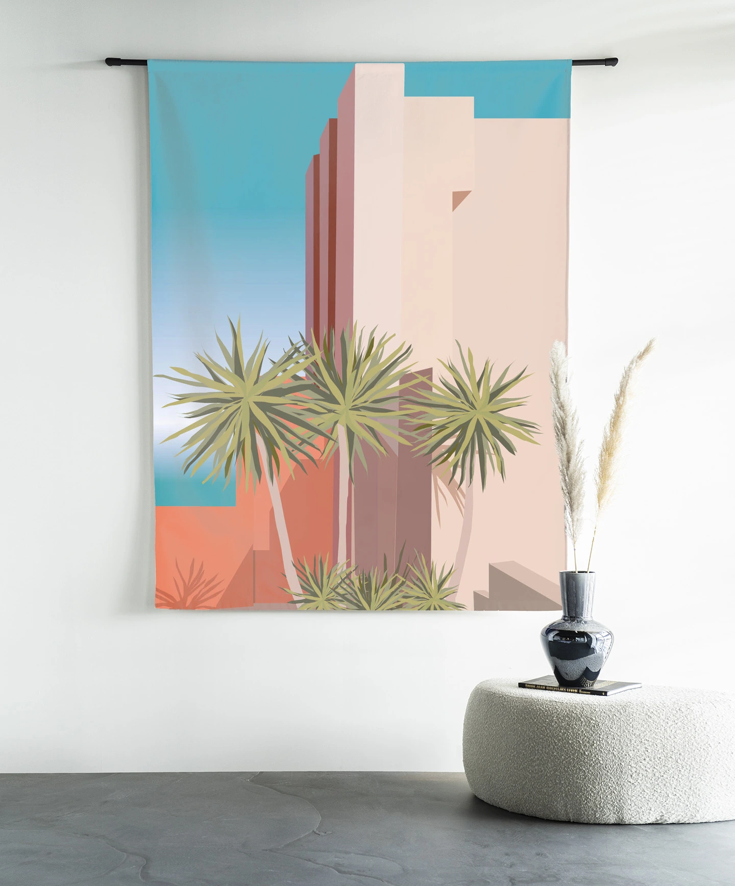 Wandkleed Tropical Place - Urban Cotton hangt aan een zwarte roede boven een wit poefje met een vaas