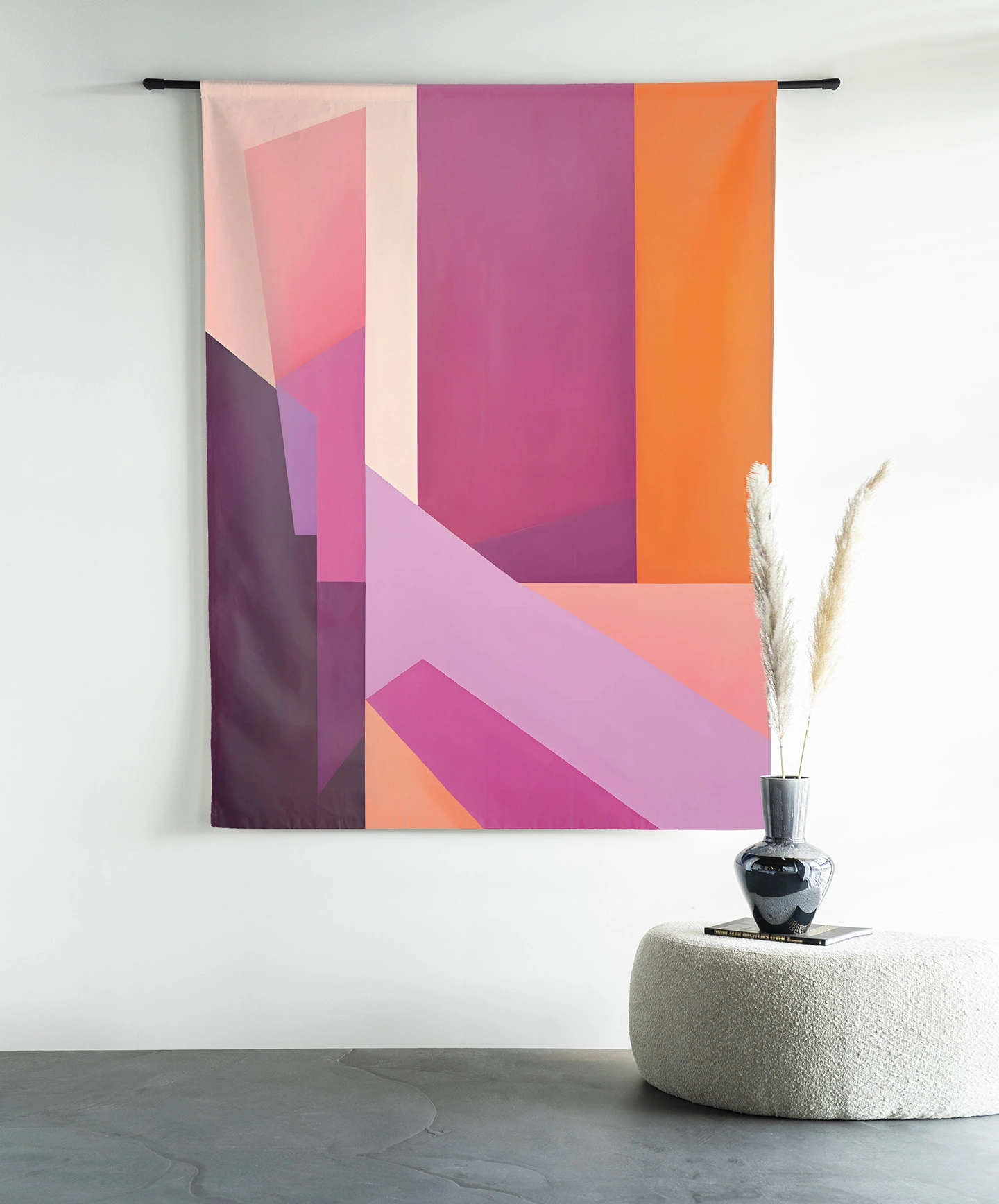 Wandkleed Folded Lines - Urban Cotton hangend aan een zwarte roede boven een poef met een vaas