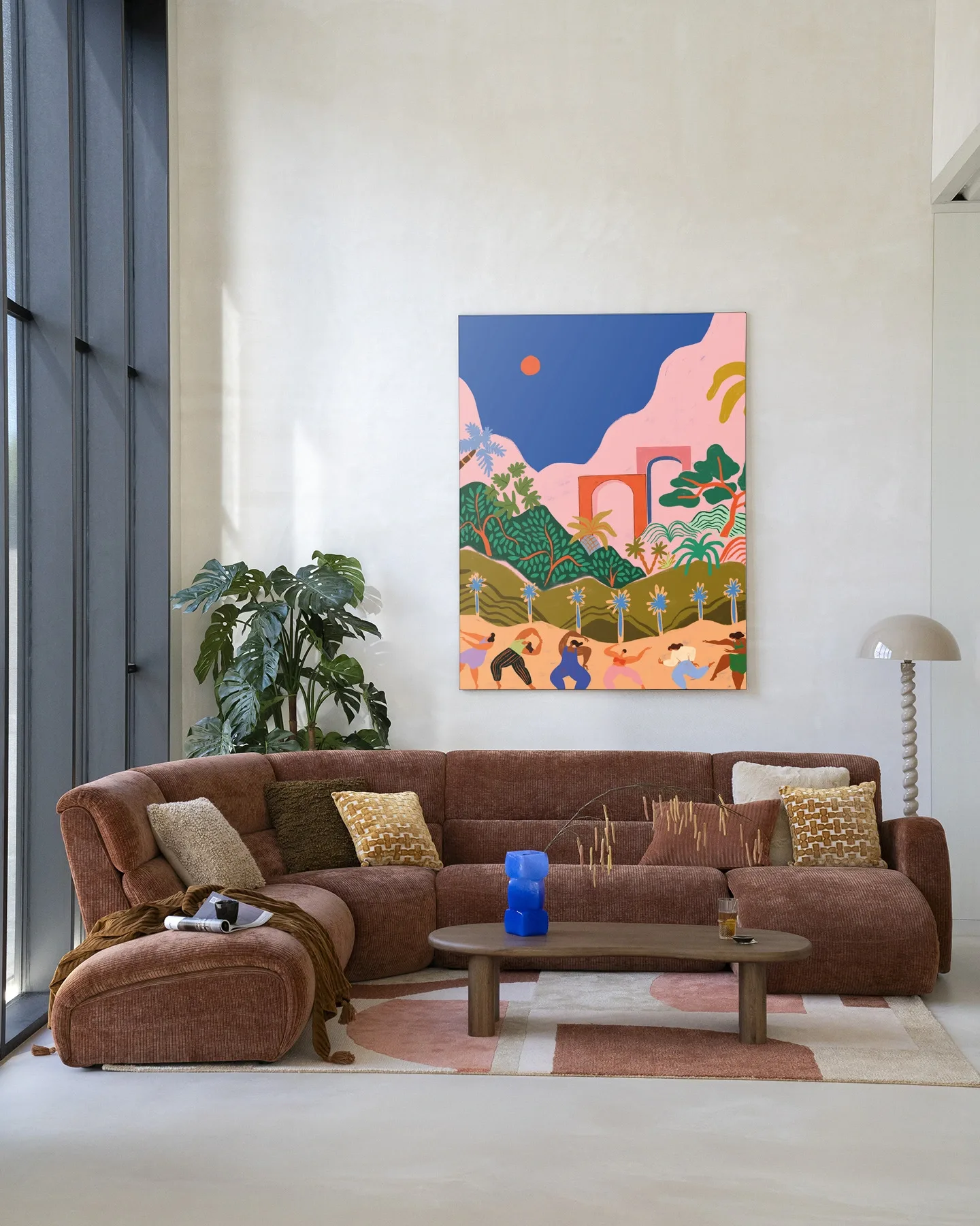 Wandkleed Dancing In Paradise - Urban Cotton hangend boven een bruine ribfluwelen hoekbank in een lichte woonkamer