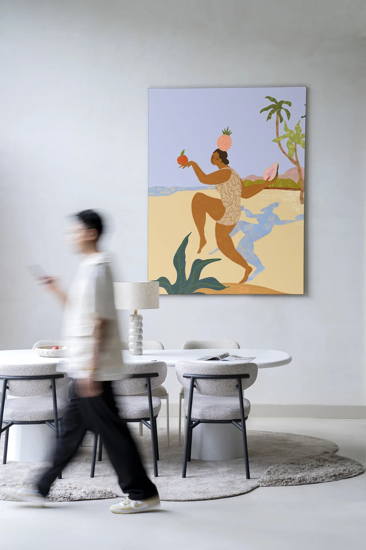 Wandkleed Balancing Act - Urban Cotton hangt aan een lichte muur boven een eettafel met stoelen