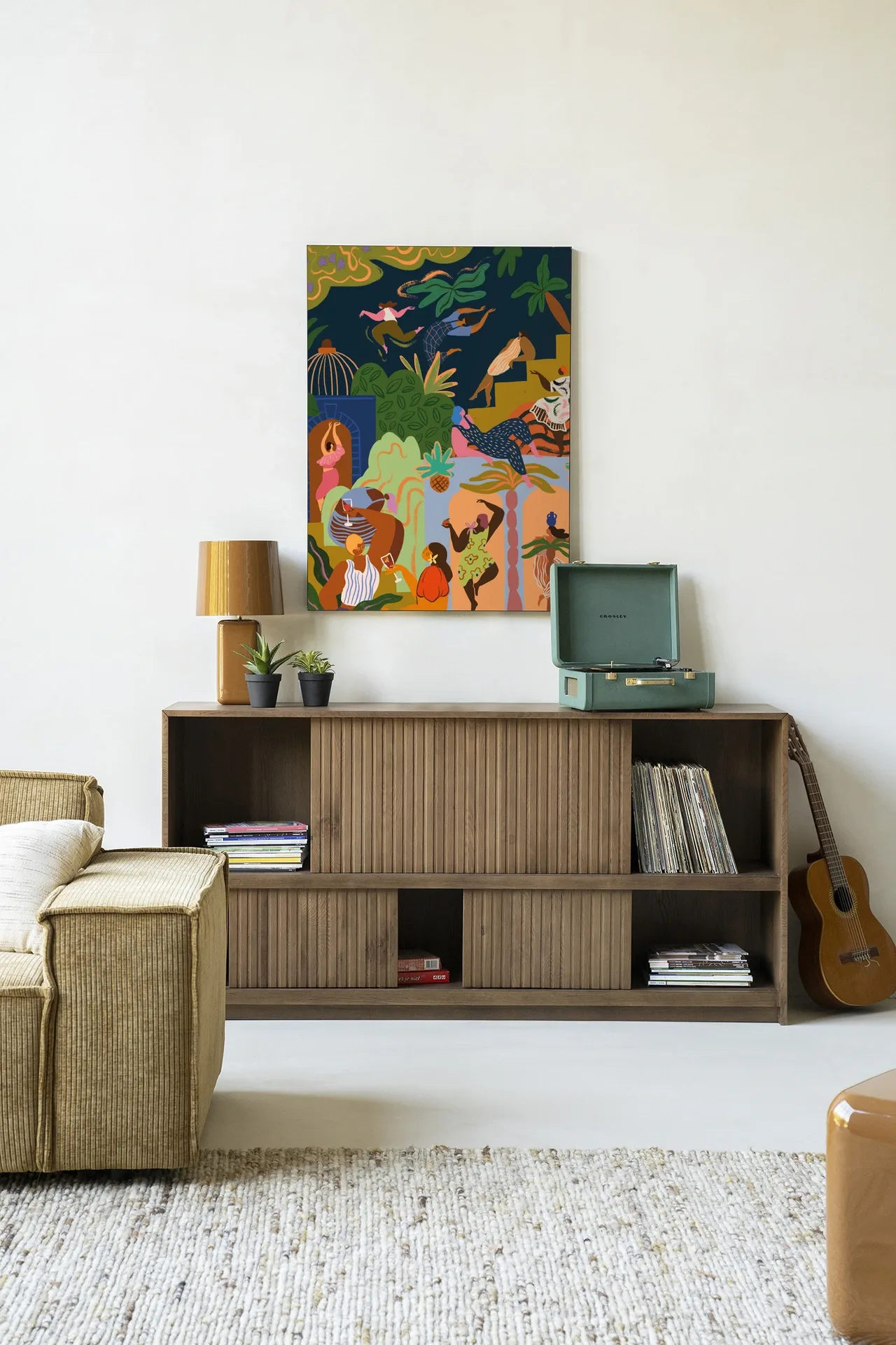 Wandkleed Fiesta - Urban Cotton hangt boven een houten dressoir in een lichte woonkamer met een bank en gitaar