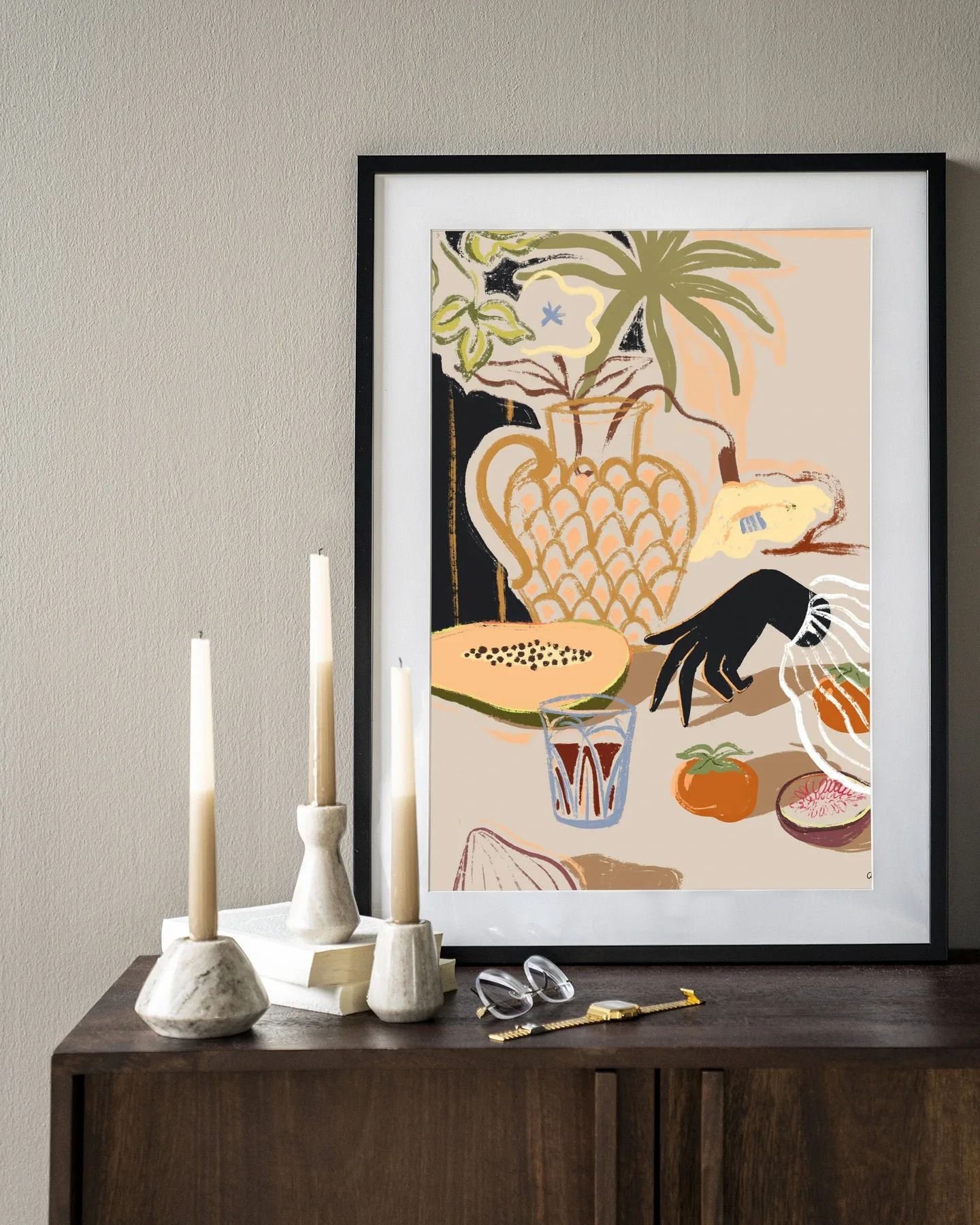 Wandkleed Fruitful Spread - Urban Cotton ingelijst aan een muur boven een houten dressoir met kaarsen