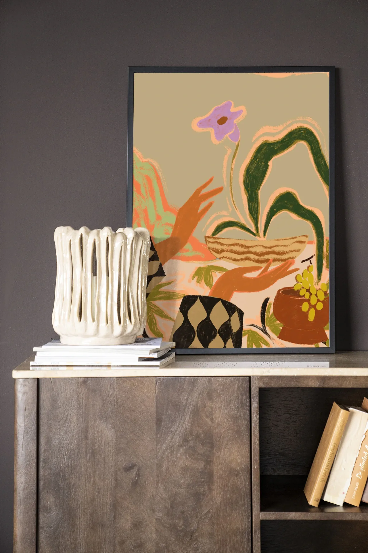 Wandkleed The Power of One - Urban Cotton ingelijst, staand op een dressoir met boeken en een vaas