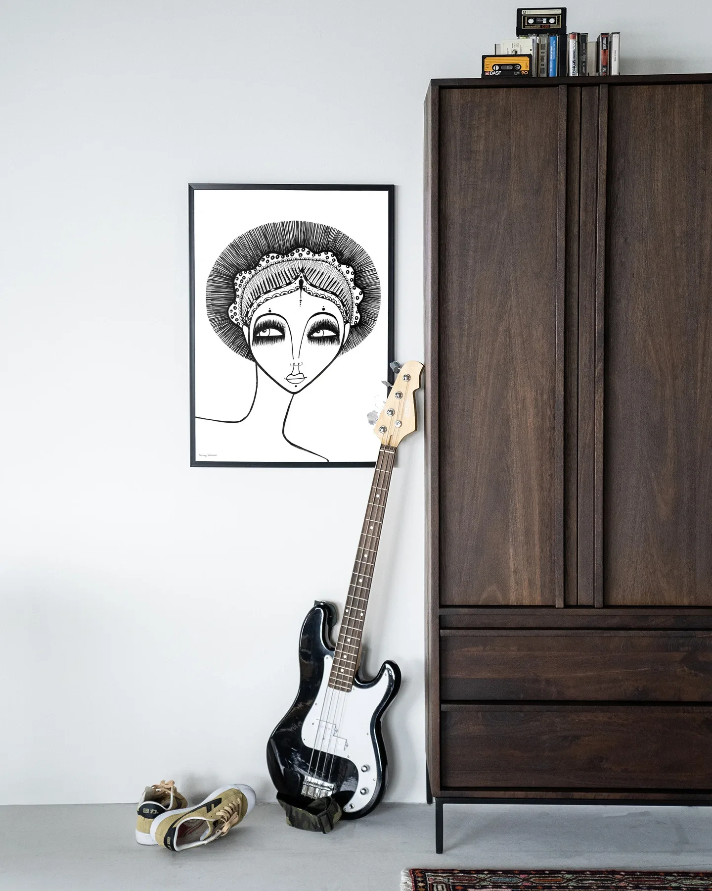 Wandkleed Leyla - Urban Cotton hangt aan een witte muur naast een donkerbruine kast met een gitaar ervoor