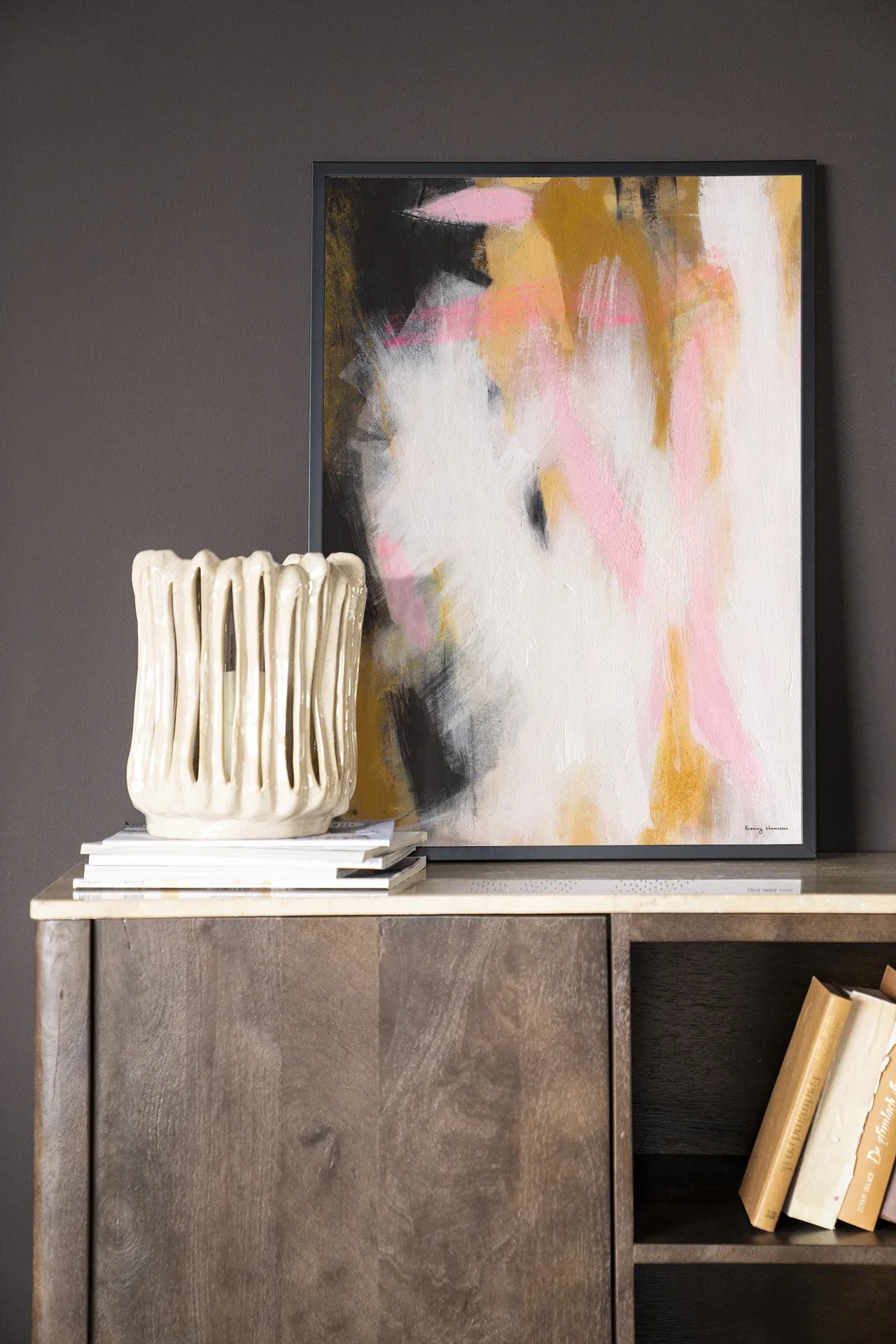 Wandkleed Abstract Moods - Urban Cotton in een lijst, staand op een houten dressoir met boeken