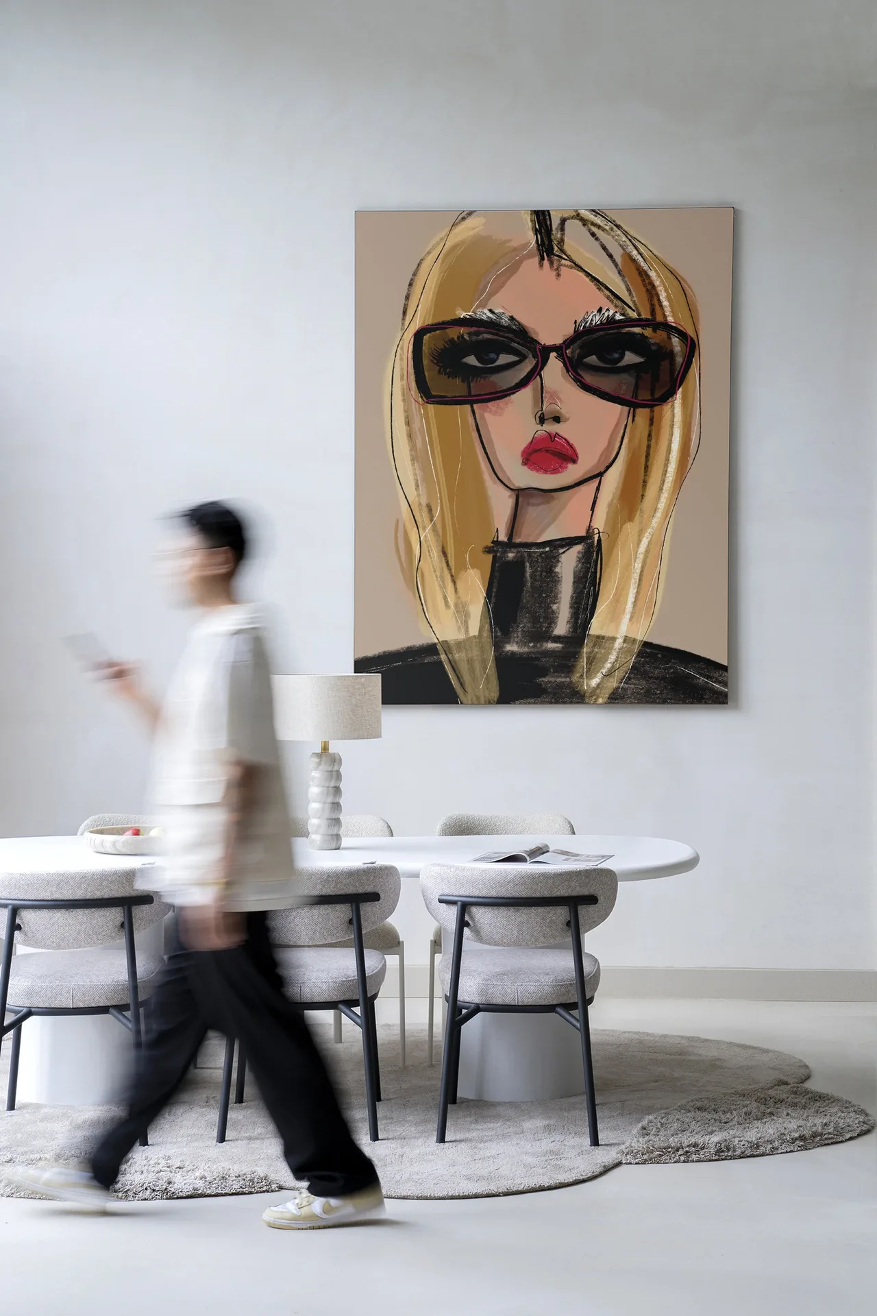 Wandkleed She Knows - Urban Cotton hangt aan een witte muur boven een eettafel met stoelen