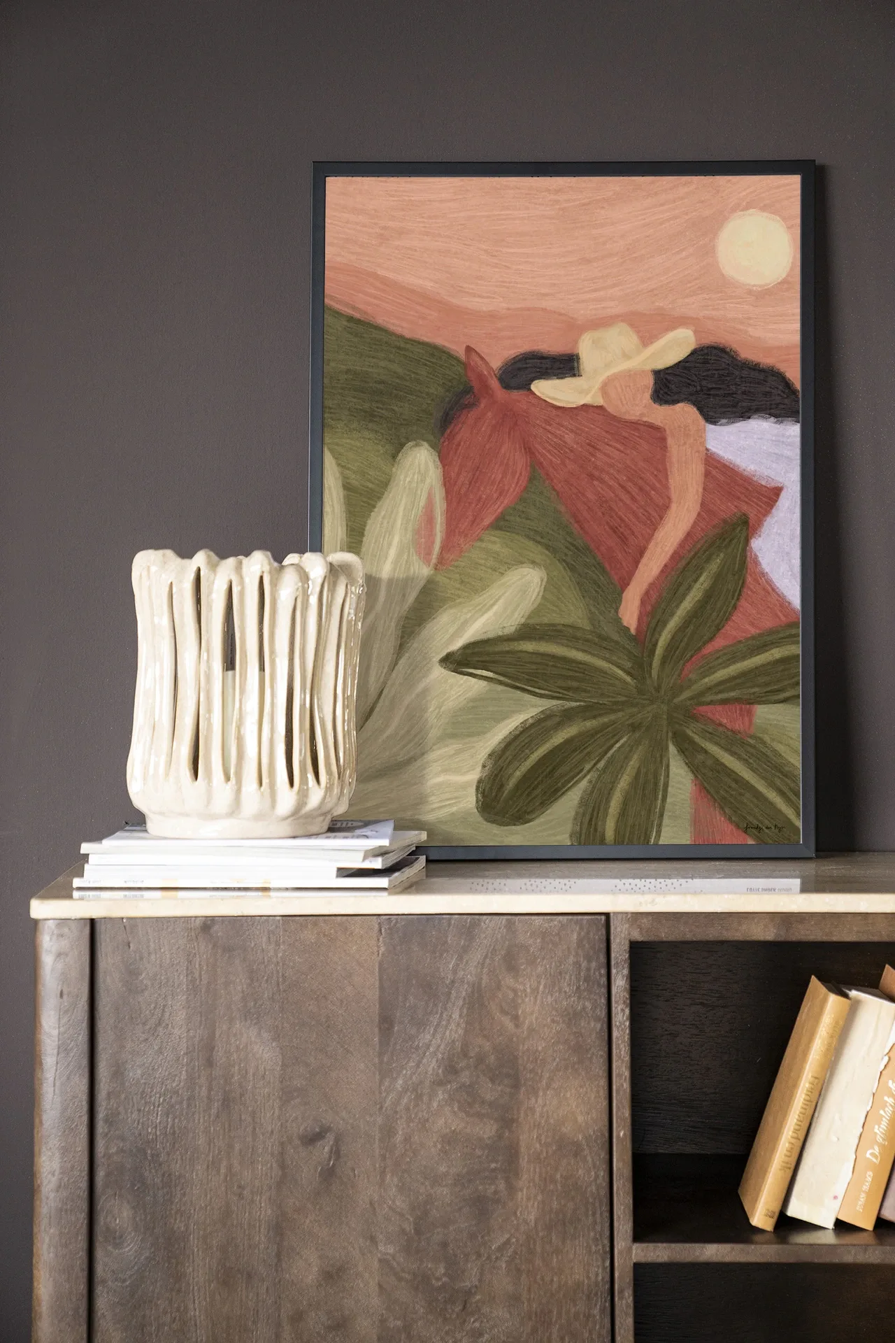 Wandkleed Horse Sunset - Urban Cotton hangend boven een houten dressoir met een vaas en boeken