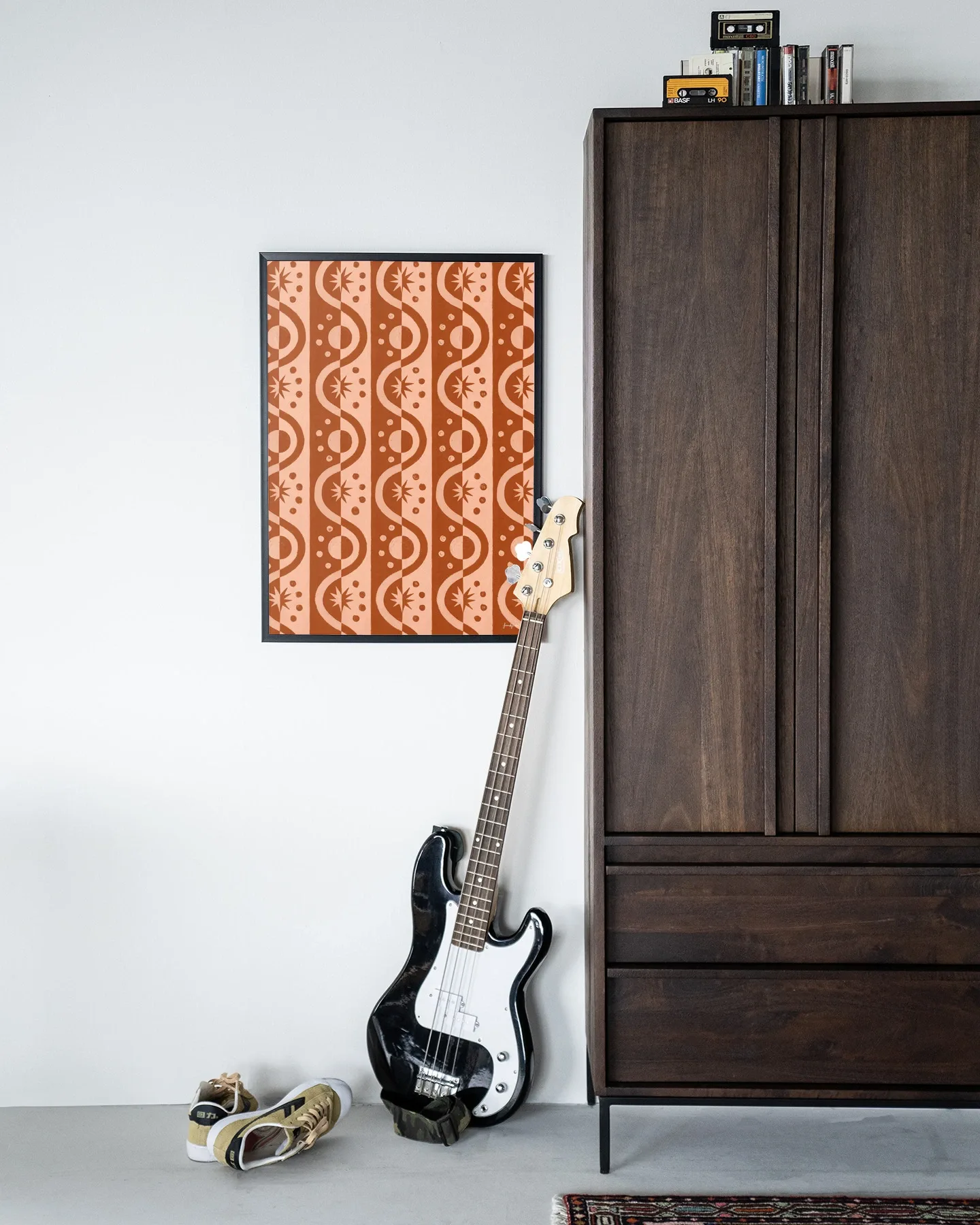 Wandteppich Moon Blockprint in einem schwarzen Rahmen neben einem dunkelbraunen Schrank mit einer Gitarre davor - Urban Cotton