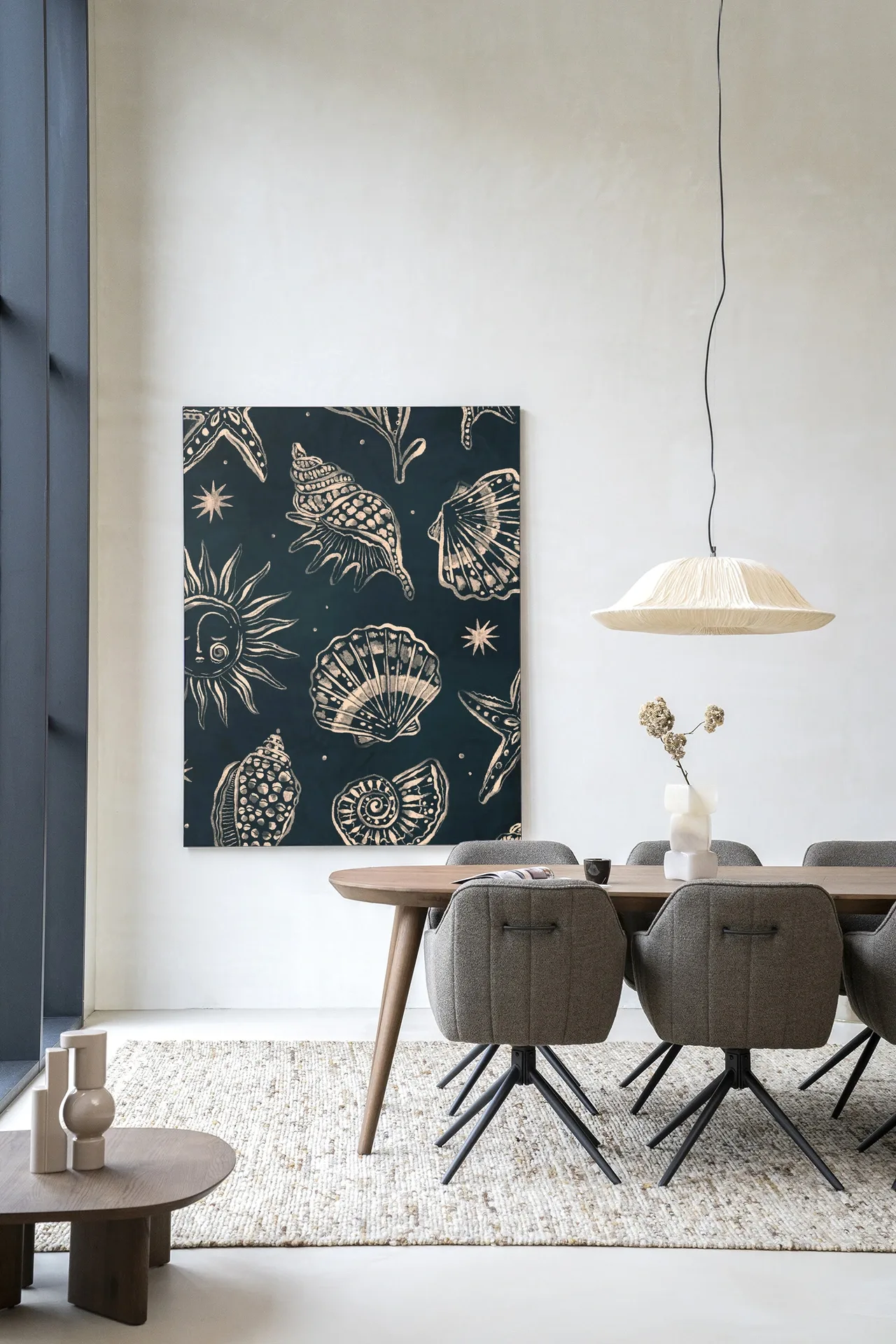 Wandkleed Seashells Midnight van Urban Cotton hangt boven een eettafel met stoelen en een vloerkleed