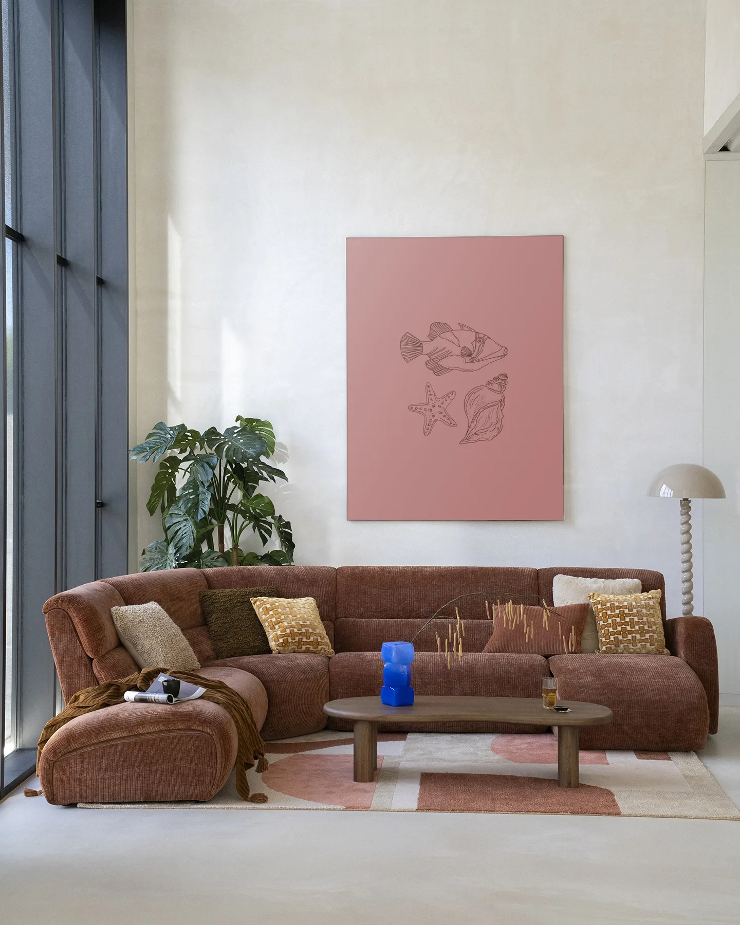 Wandkleed Tres Pisces - Urban Cotton hangt aan een lichte muur in een woonkamer met bruine bank